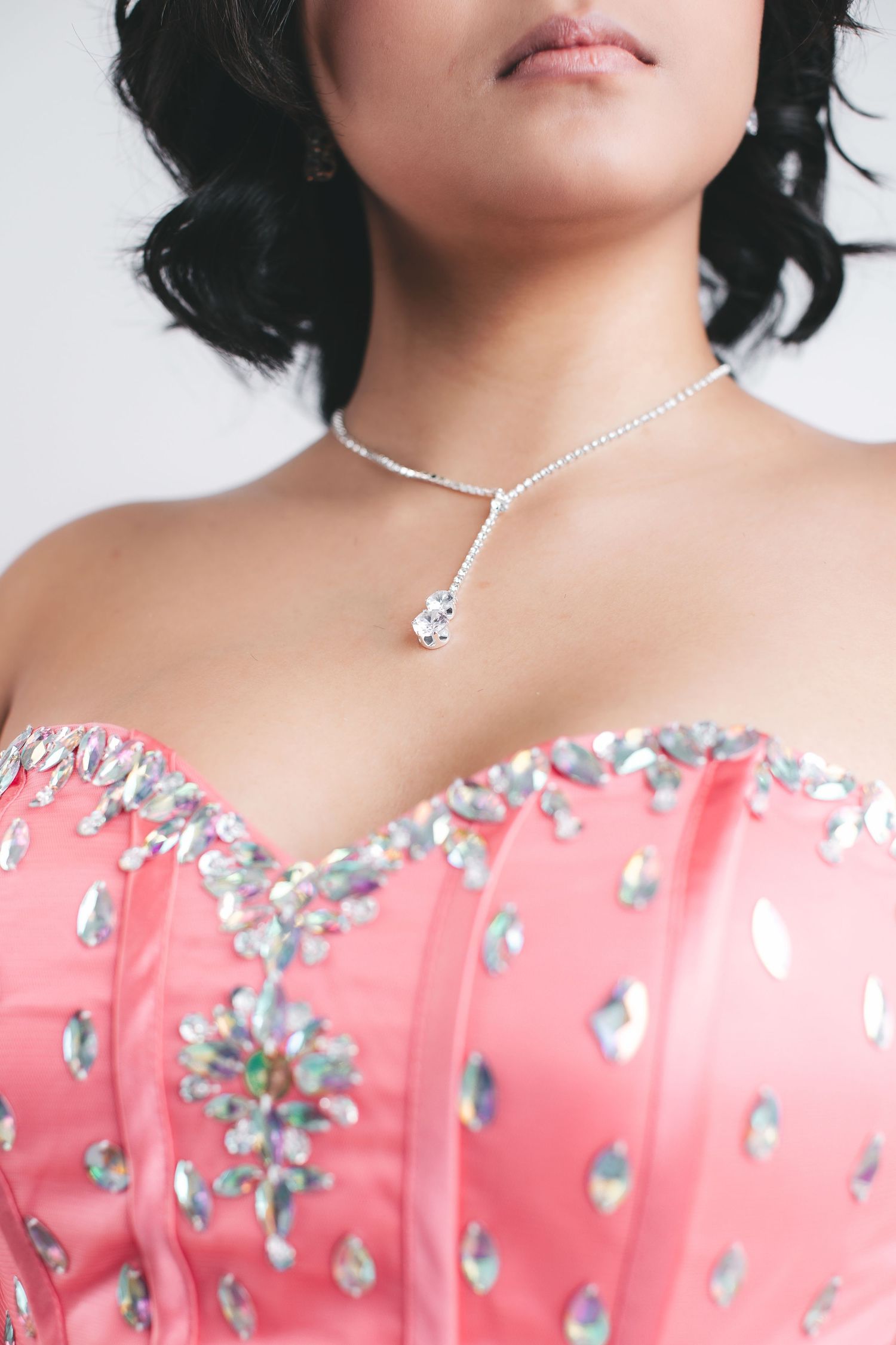 Close-up of woman in pink rhinestone corset dress wearing a delicate crystal drop necklace.