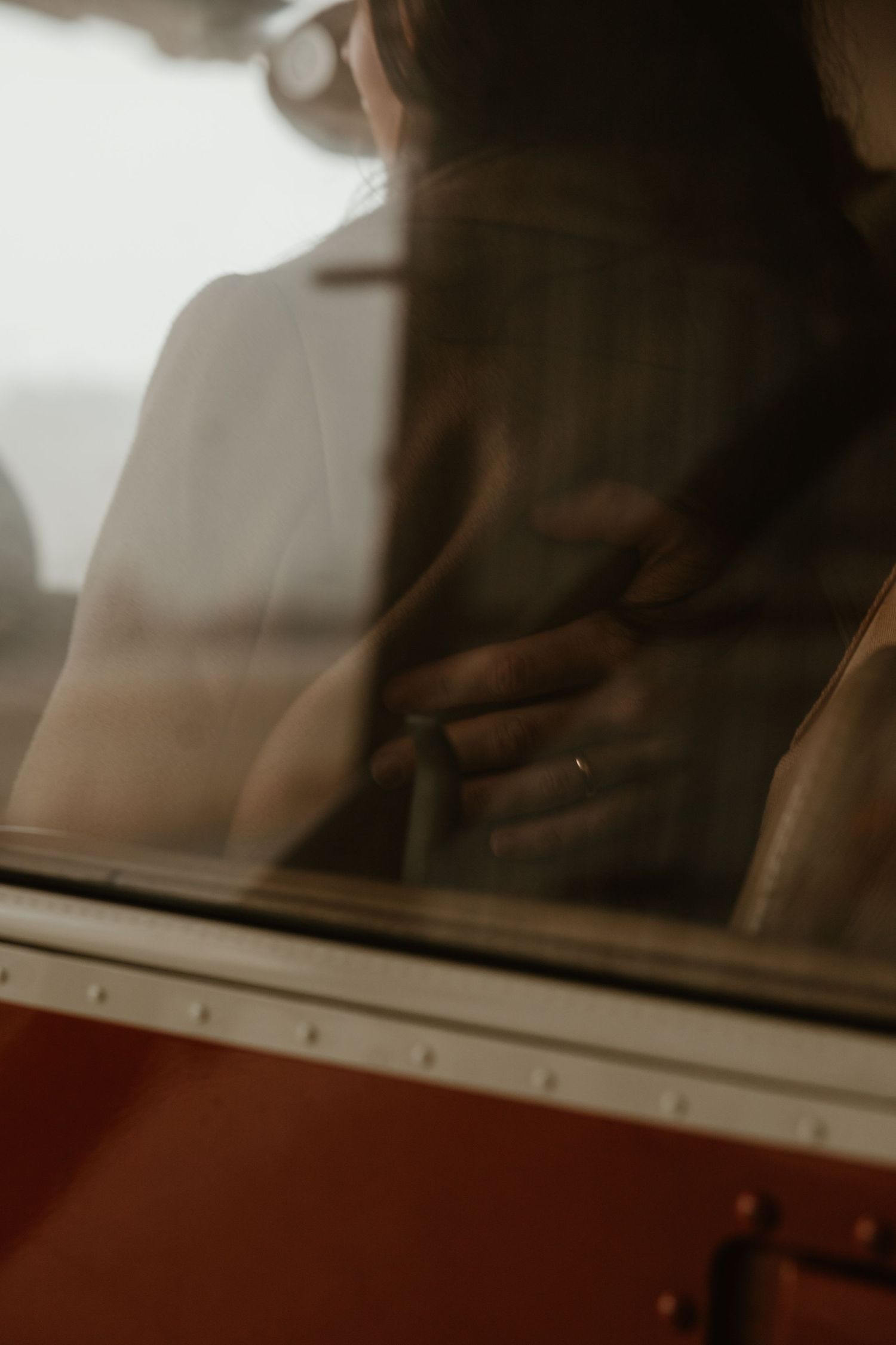 Intimate reflection of a couple through a vintage airplane window during an engagement session.