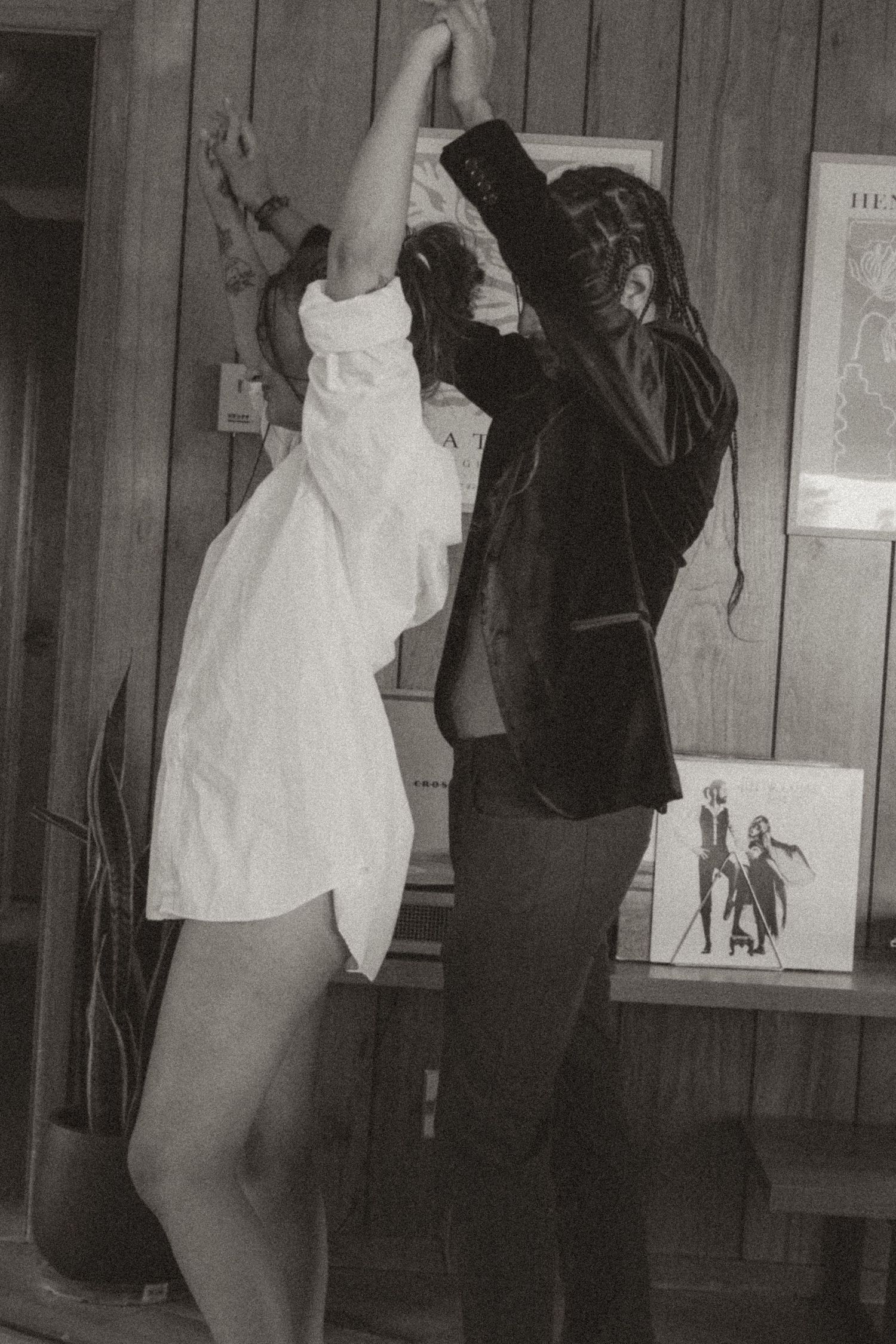 Black and white photo of couple dancing joyfully in a rustic wood-paneled room.