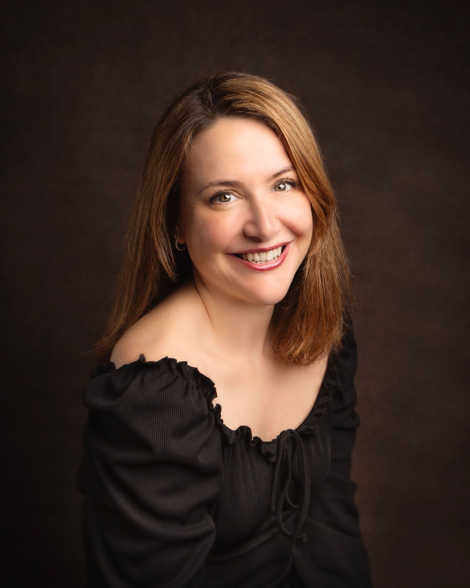 Smiling woman with auburn hair in black off-shoulder top posing for studio portrait  in Birmingham