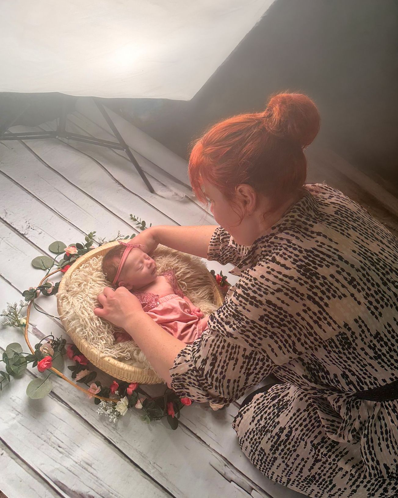 Gemma Harte poses a newborn baby resting in a wicker basket with flowers, in Wolverhampton