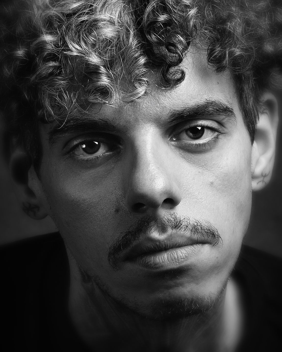 Black and white close-up portrait of young man with curly hair and mustache  in Birmingham