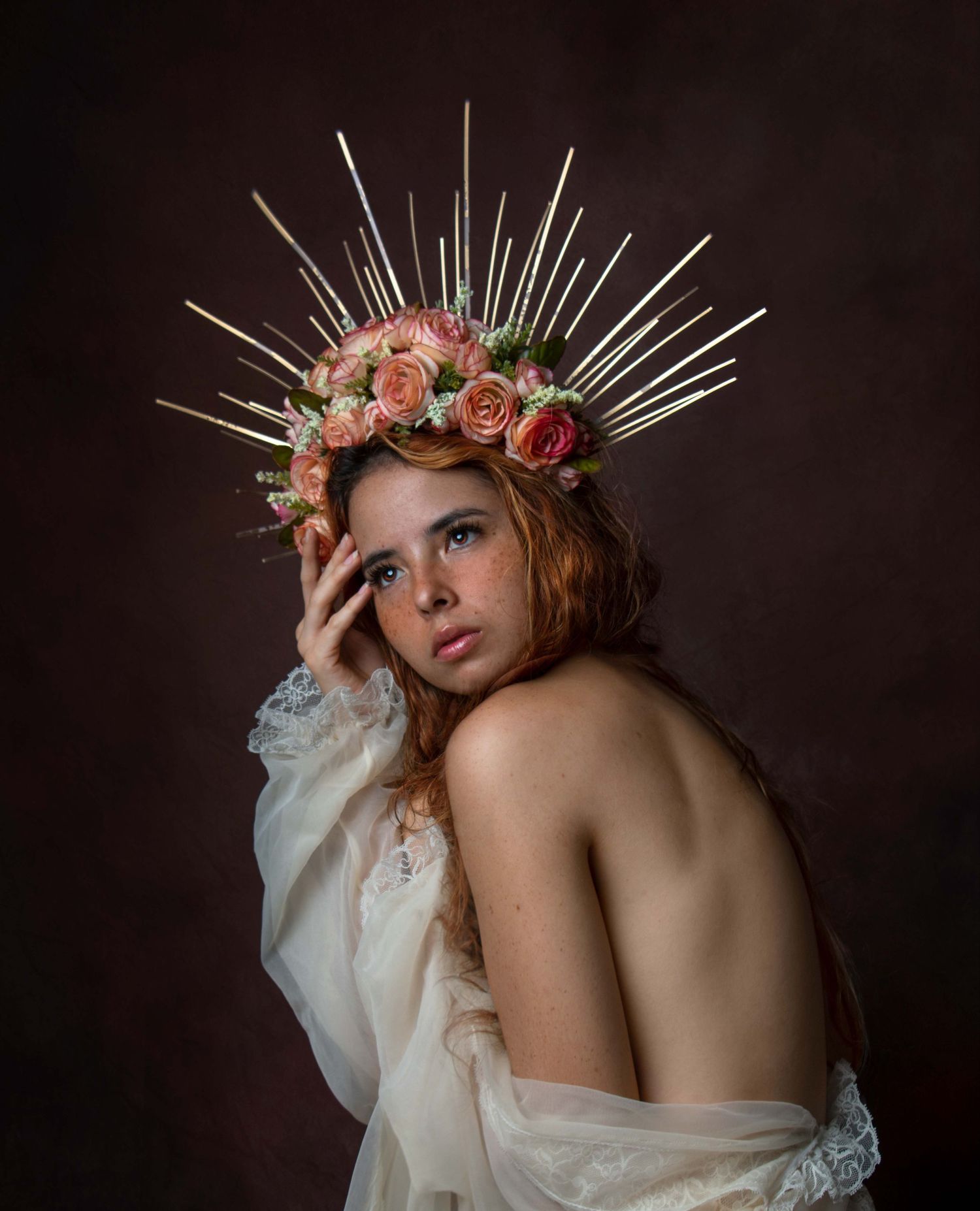 Ethereal portrait featuring delicate pink roses and metallic spikes arranged in a crown against a dark background.