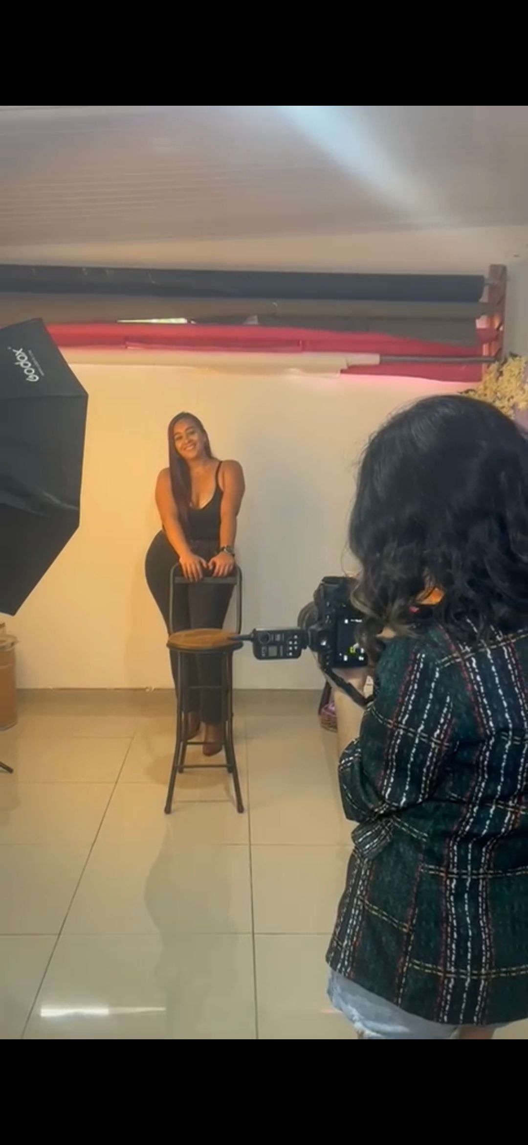 Behind the scenes photo of a professional photography shoot in a studio with lighting equipment.