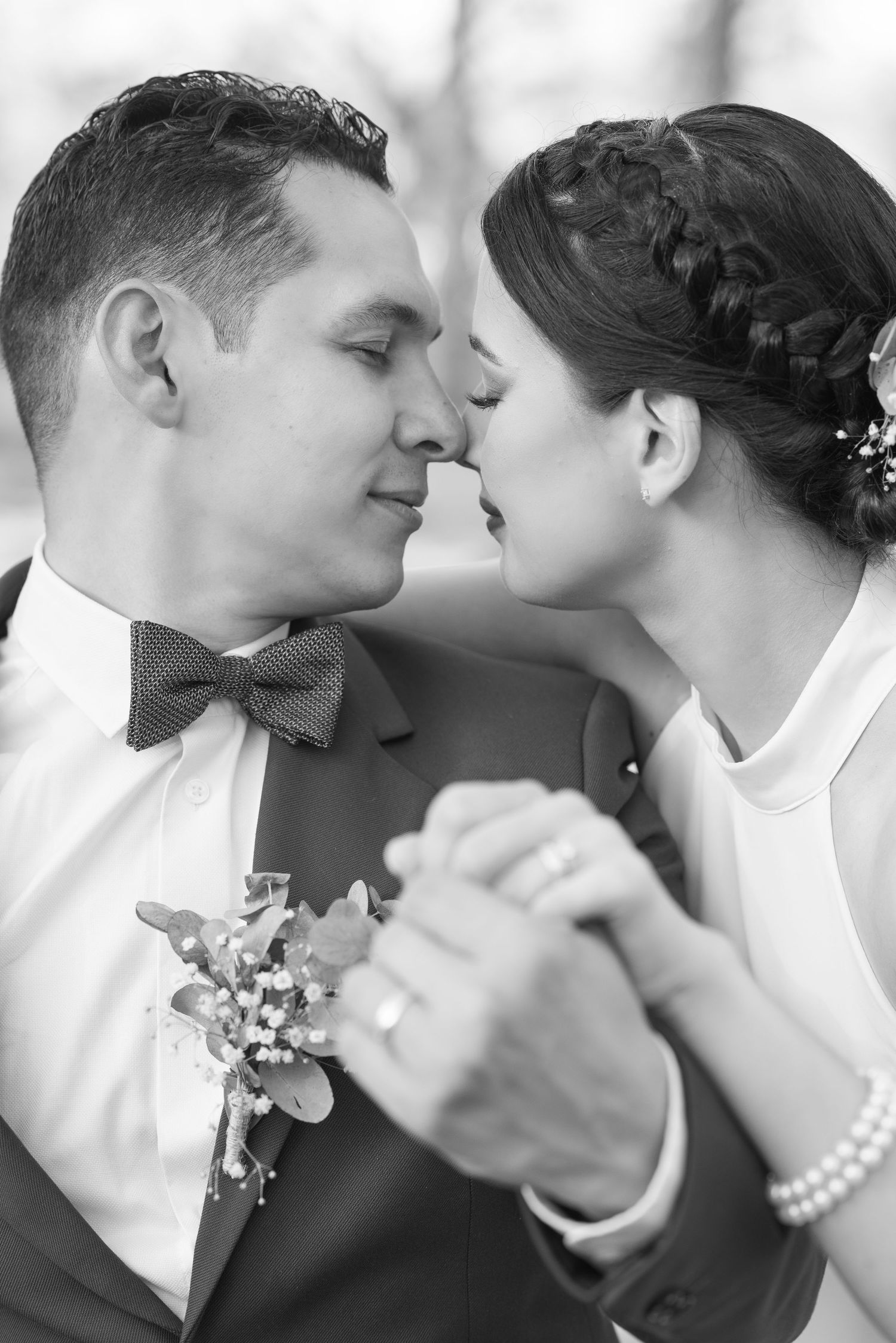Intimate black and white portrait of couple about to kiss, showcasing classic wedding attire.