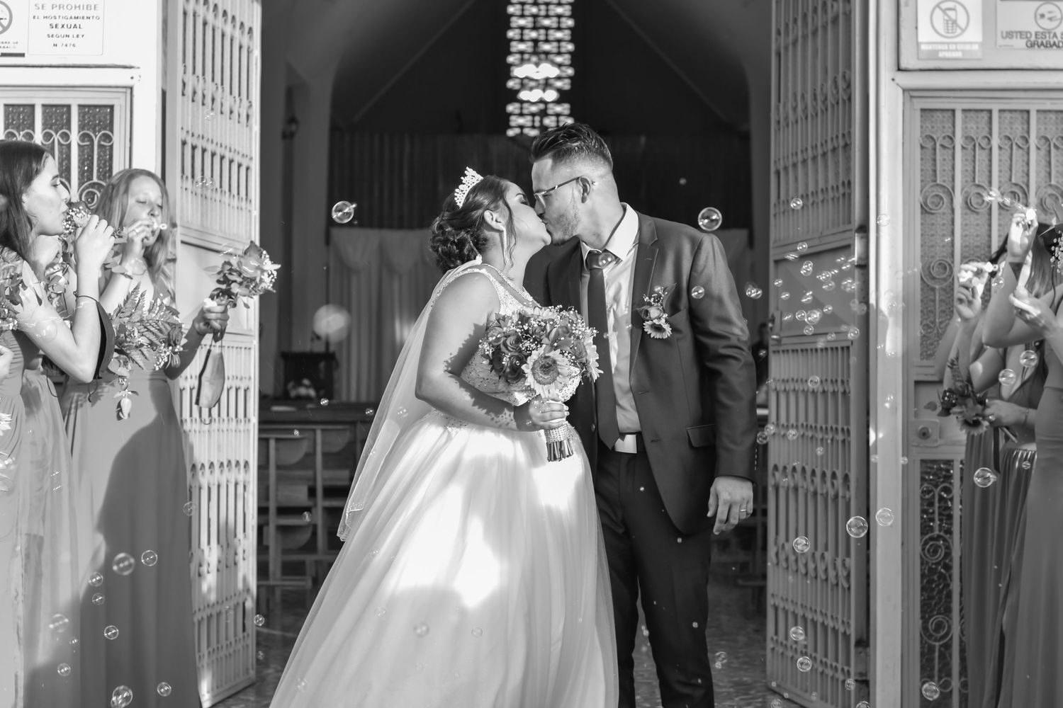 Newlyweds share a joyful moment exiting a church while guests shower them with confetti.