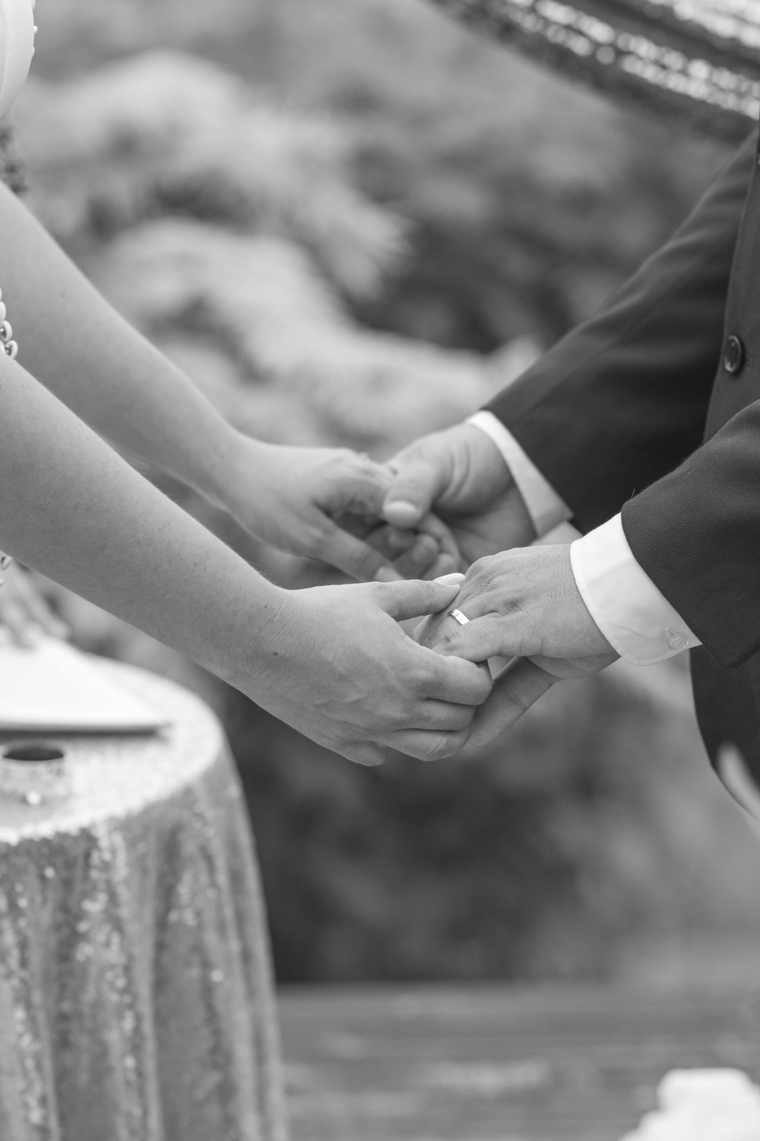Black and white photo of newlyweds holding hands during wedding ceremony.