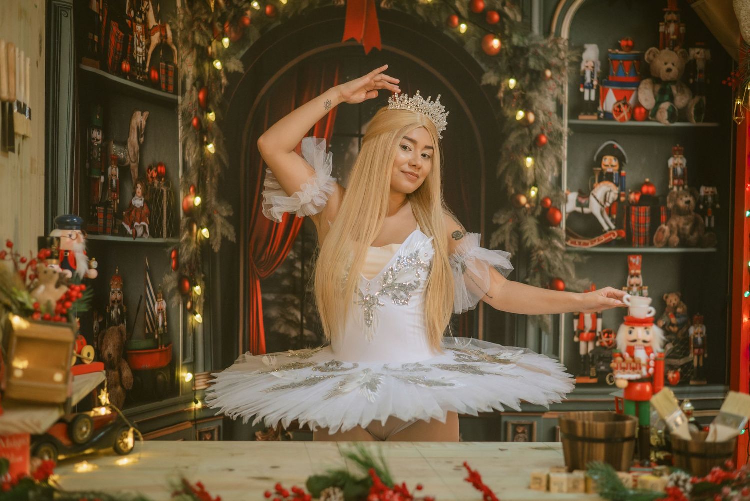 Ballet dancer in white tutu performs in a magical Christmas setting surrounded by nutcrackers and twinkling lights.