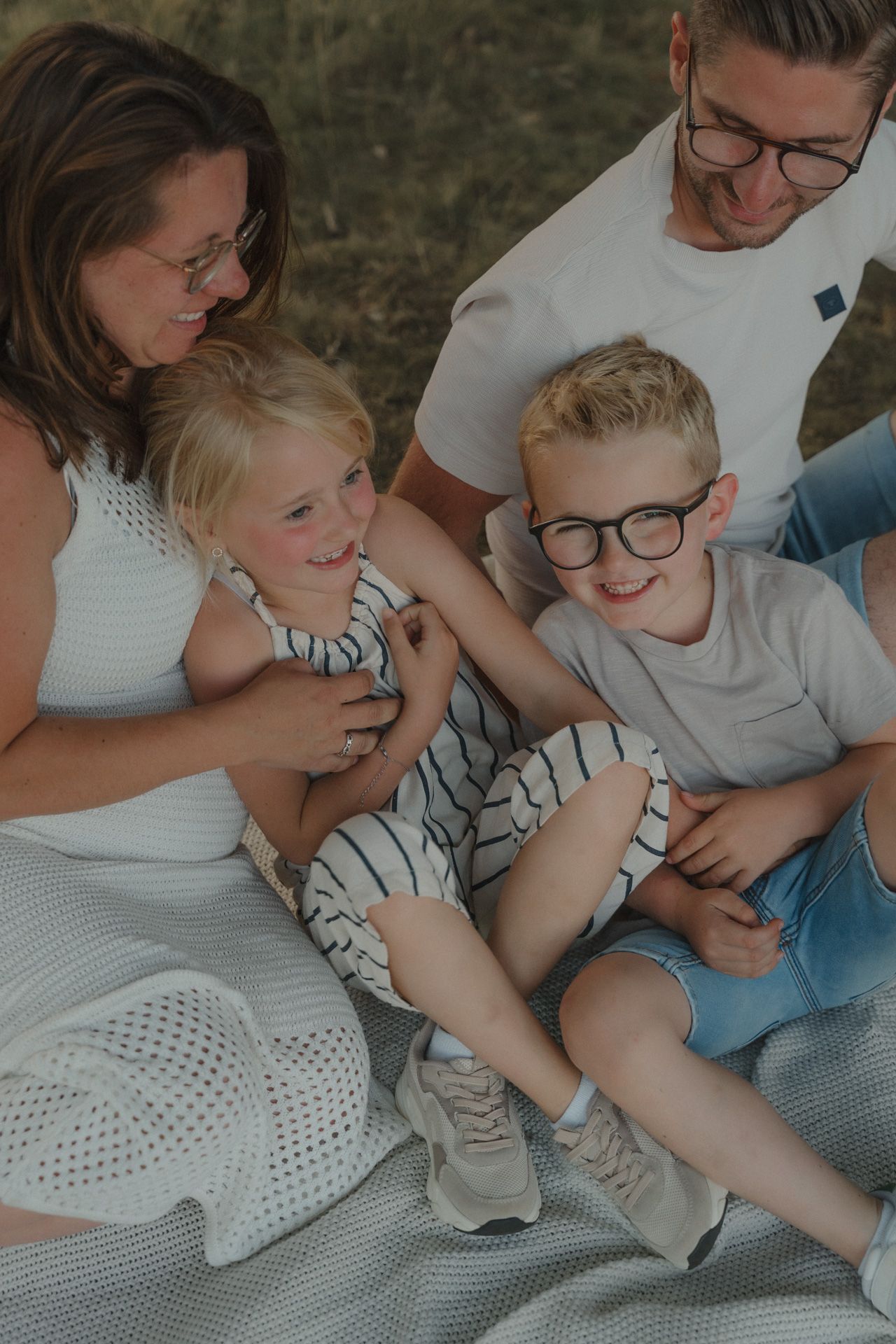 Gezin met twee kinderen tijdens een spontaan en speels moment bij een gezinsshoot