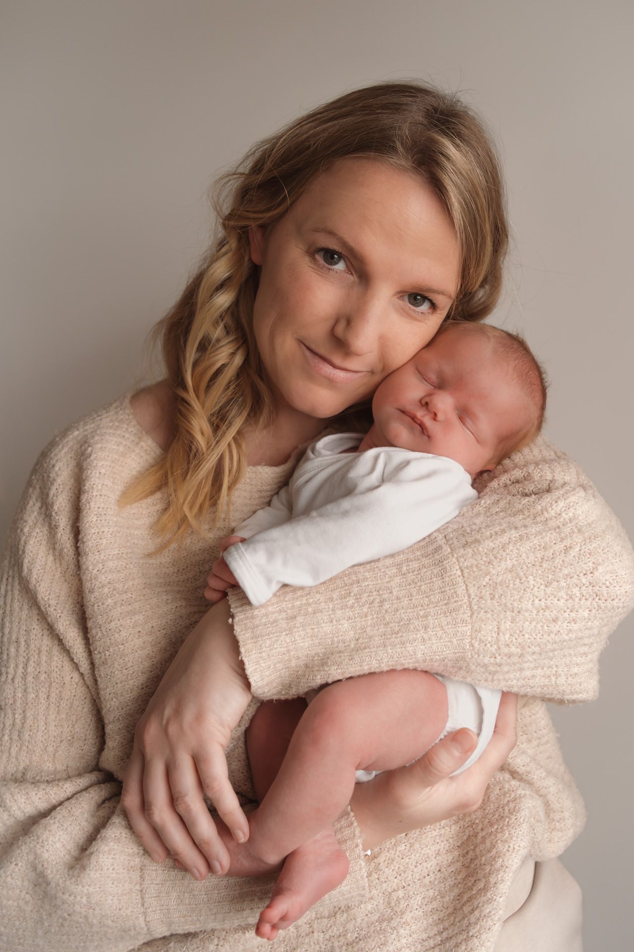 Mama met haar slapende newborn in de armen tijdens een warme newbornshoot