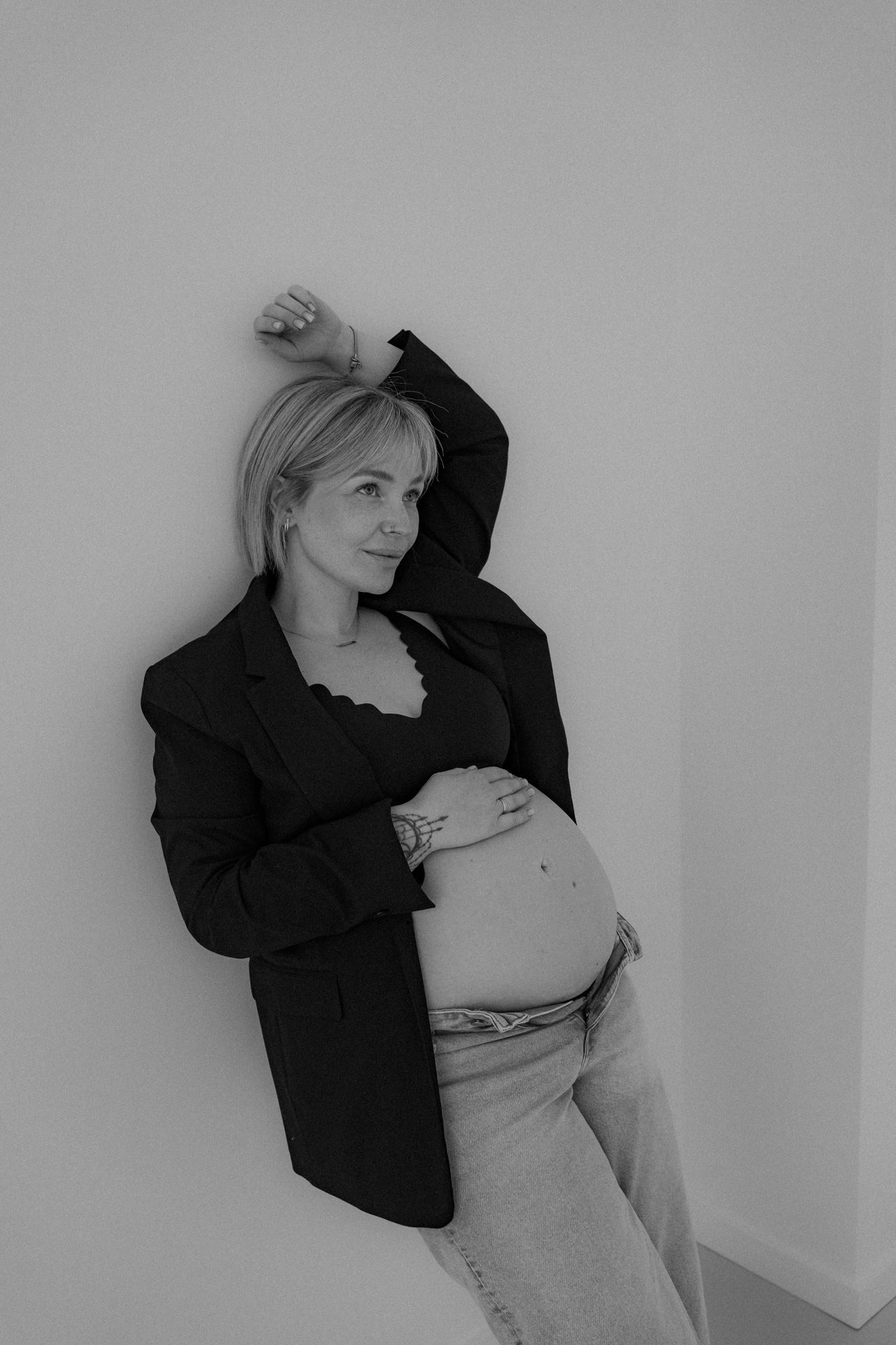 Zwangere vrouw met hand op de babybuik tijdens een zwart-wit zwangerschapsshoot in de studio