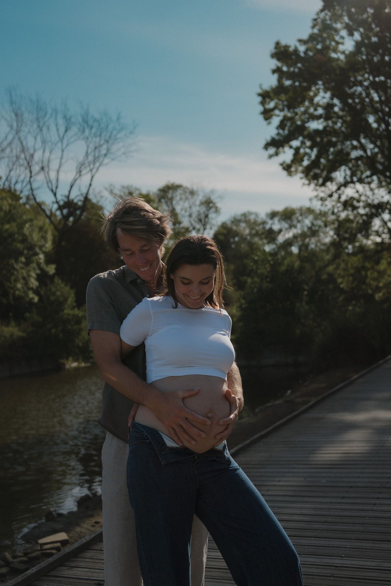 Zwanger koppel omarmt de babybuik tijdens een zwangerschapsshoot in een park in Mechelen