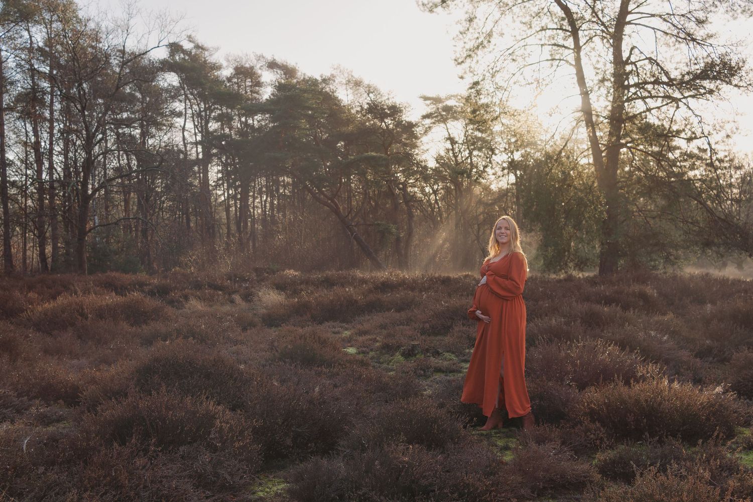 Zwangere vrouw op de heide tijdens een zwangerschapsshoot bij zonsopgang