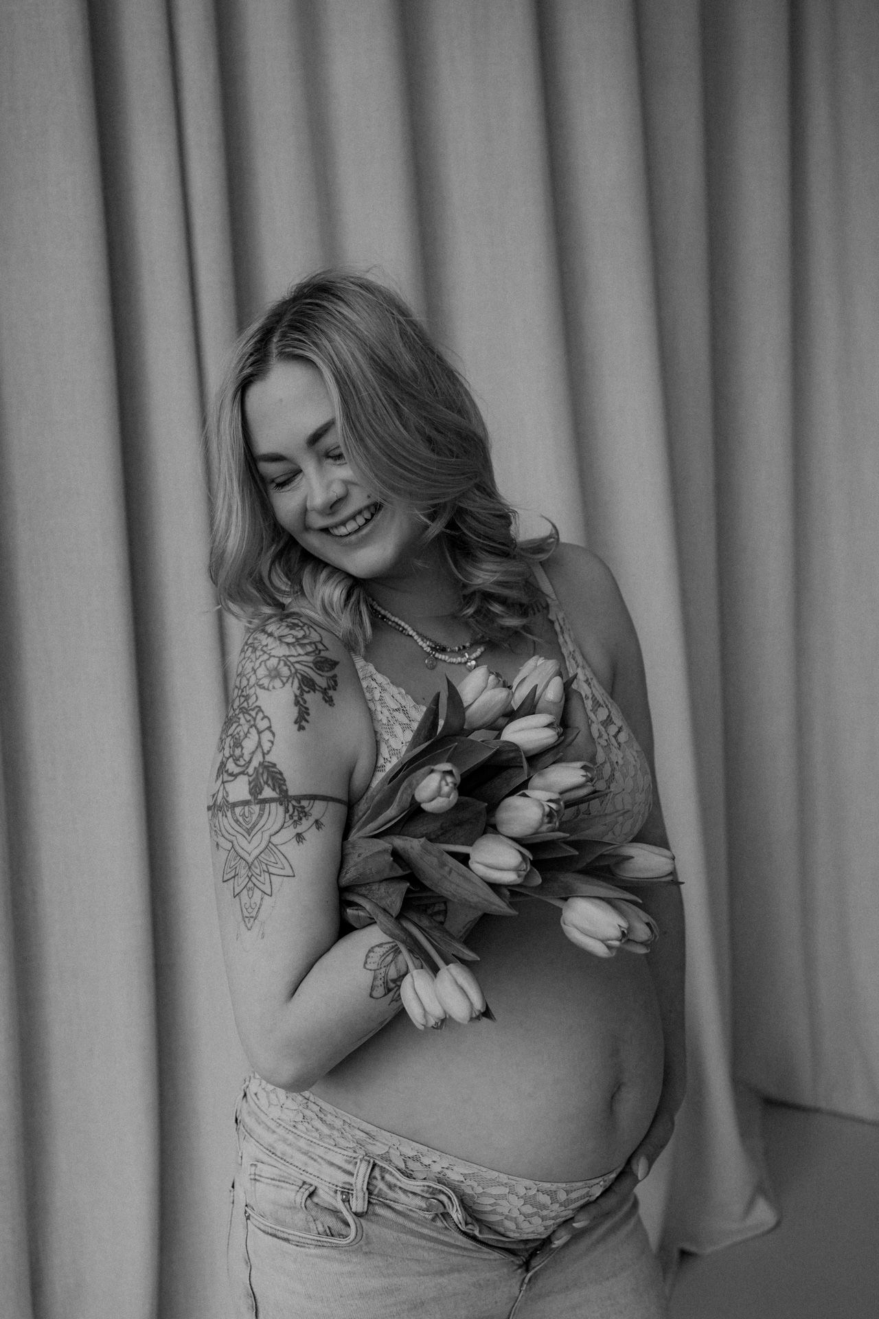 Zwangere vrouw met bloemen tijdens een zwart-wit zwangerschapsshoot in de studio
