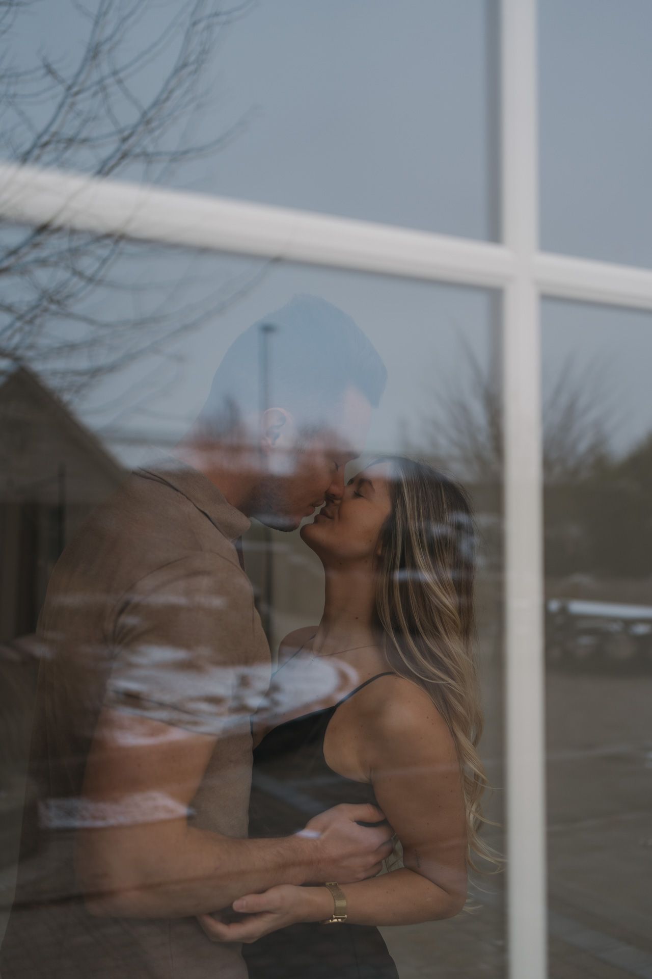 Koppel tijdens een intiem moment gefotografeerd door het raam tijdens een koppelshoot