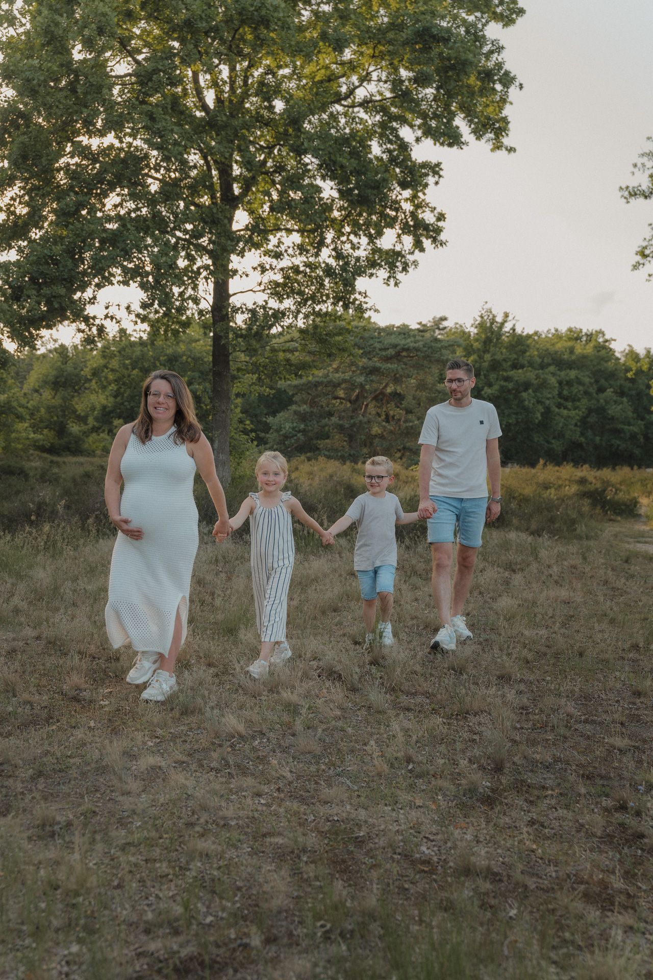 Zwanger gezin met twee kinderen tijdens een gezinsshoot in de natuur