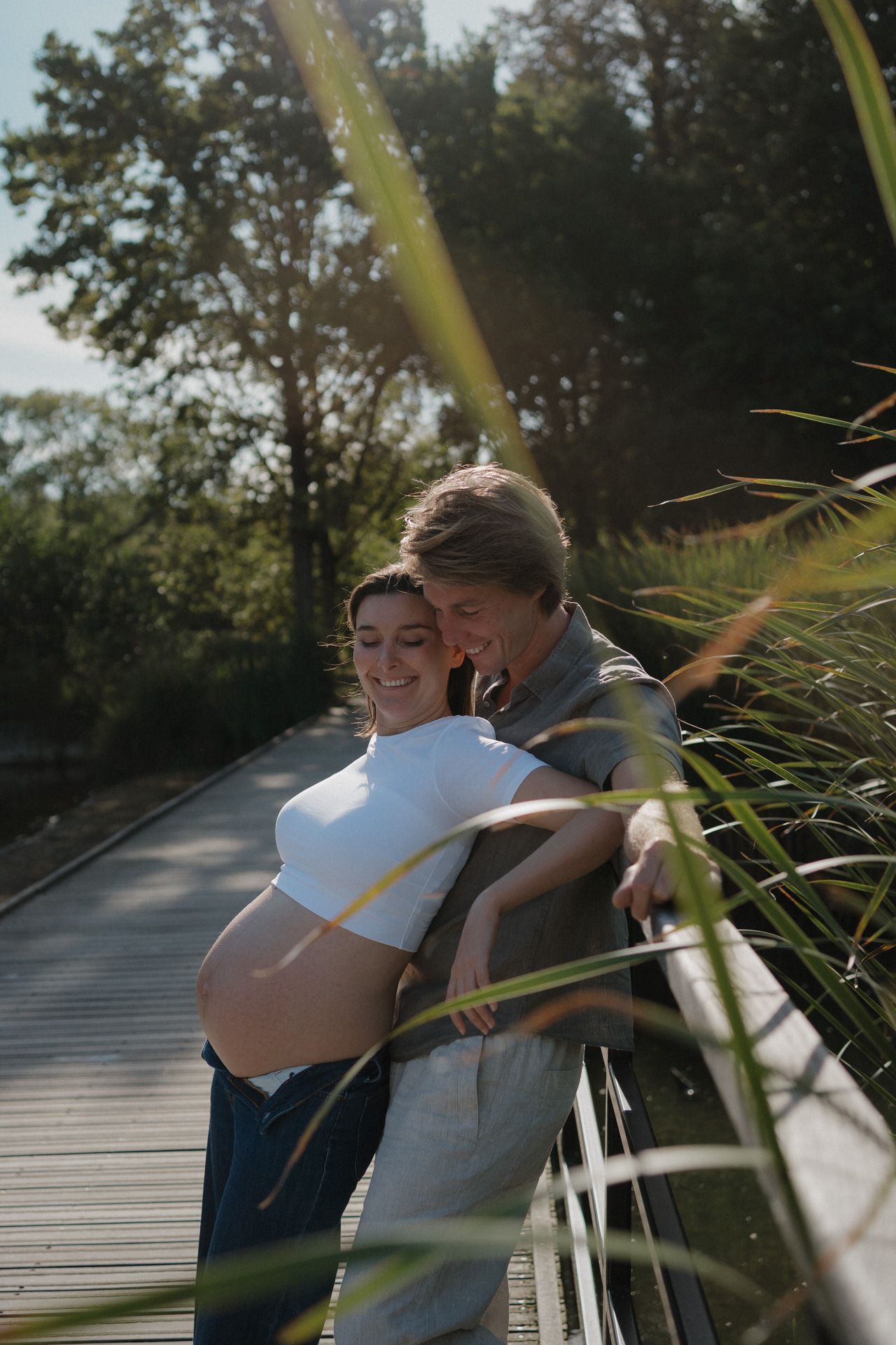 Zwanger koppel tijdens een liefdevol moment bij een zwangerschapsshoot in een park in Mechelen