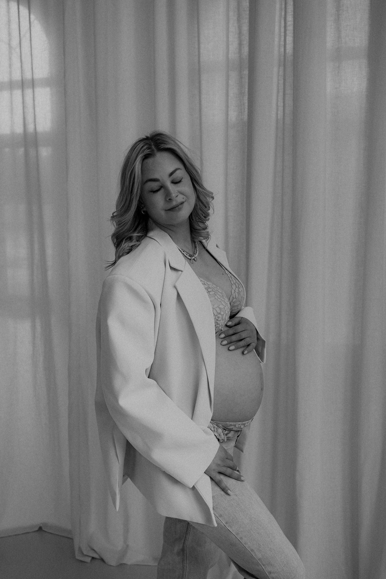Zwangere vrouw met handen op de babybuik tijdens een zwart-wit zwangerschapsshoot in de studio
