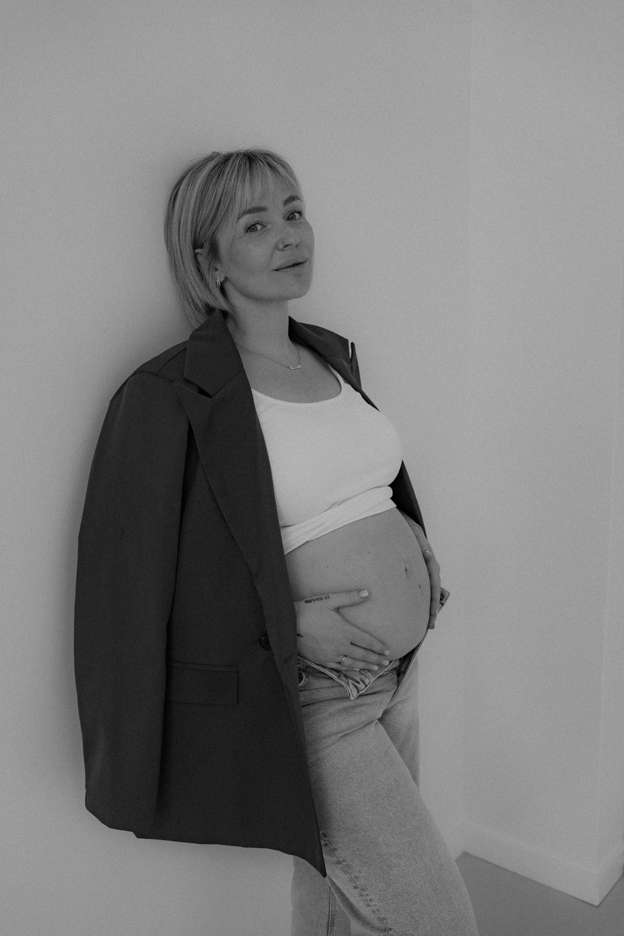 Zwangere vrouw met handen op de babybuik tijdens een zwart-wit zwangerschapsshoot in de studio