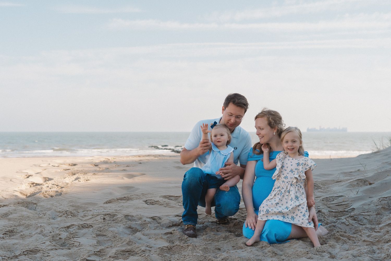 Zwanger gezin met twee kinderen tijdens een ontspannen zwangerschapsshoot op het strand