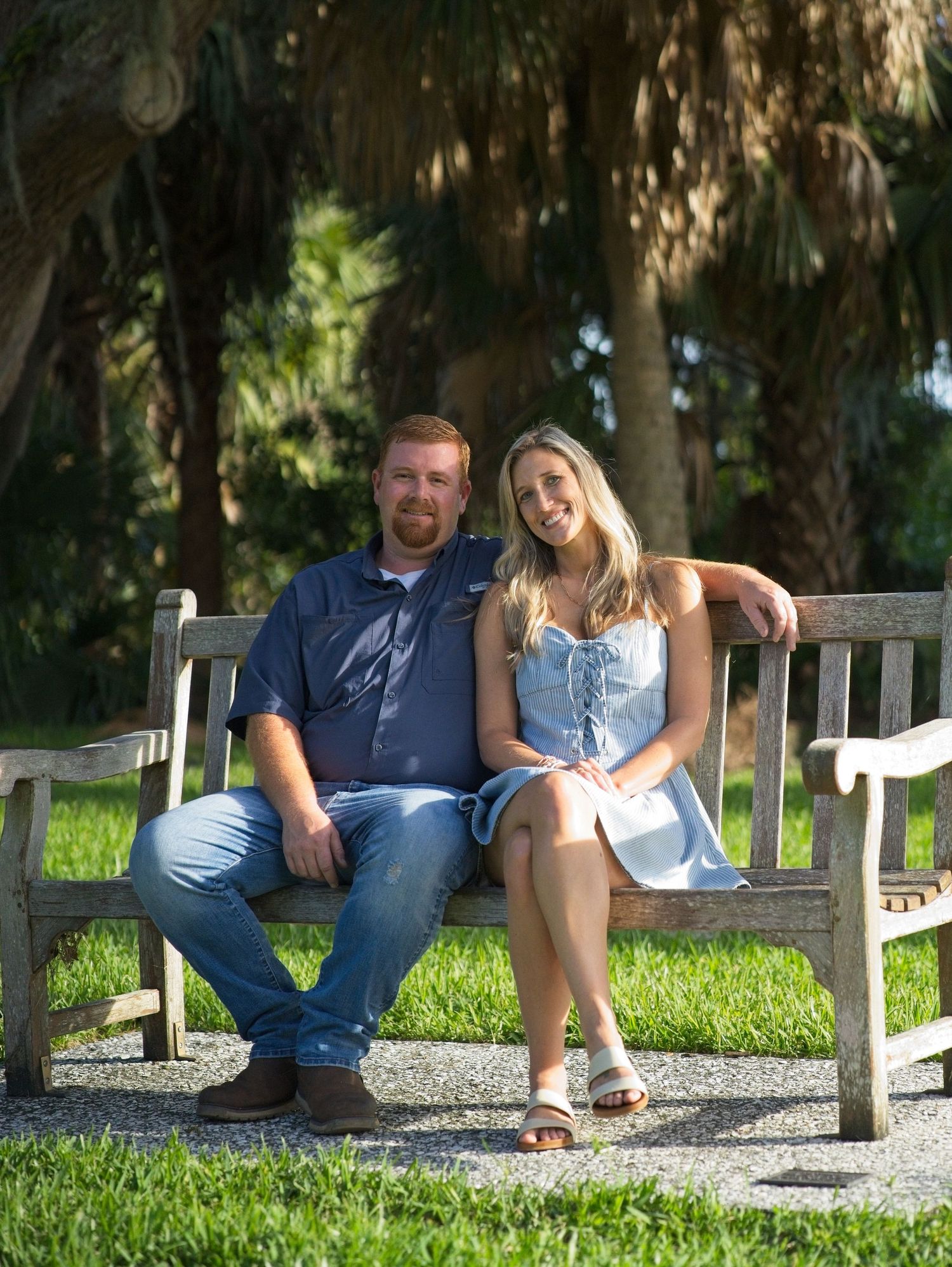 Couple sitting together on a rustic wooden bench in a scenic outdoor park setting.