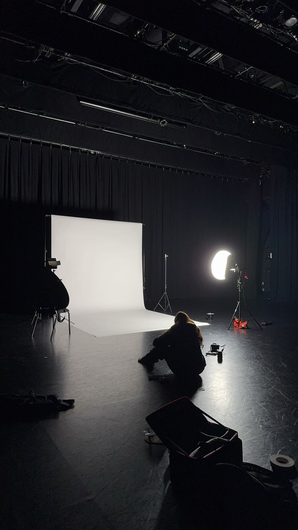 Professional photo studio setup with white backdrop and softbox lighting on black stage.