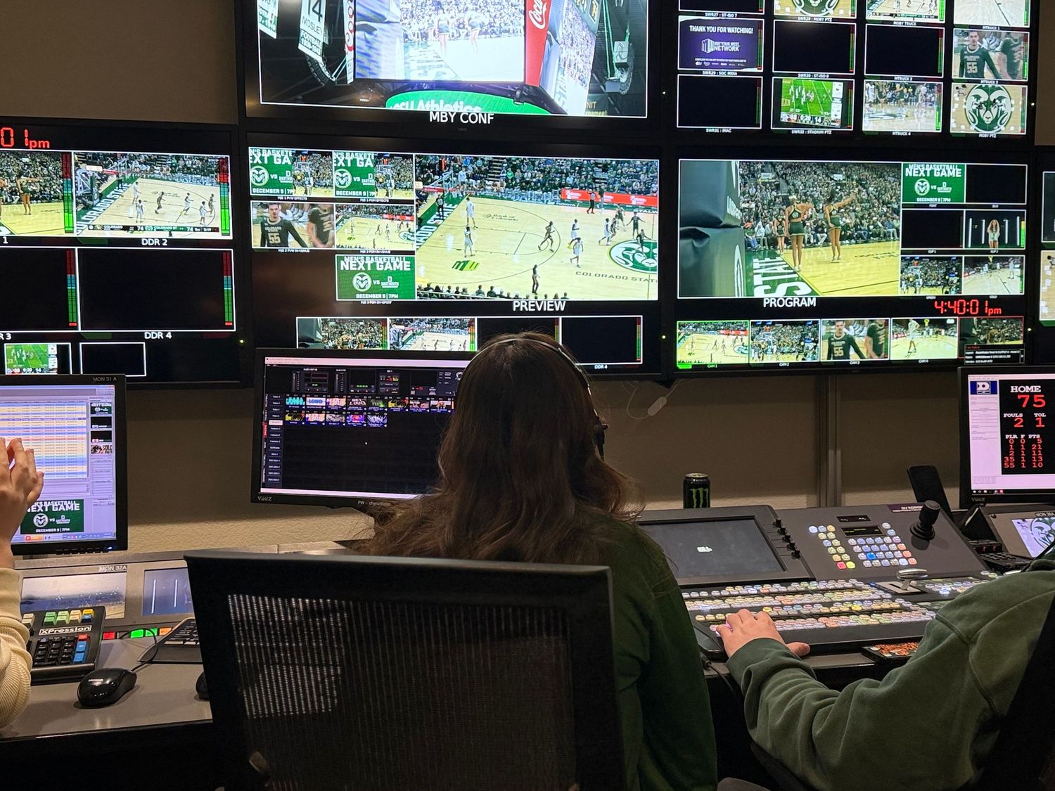 Broadcast control room operator managing multiple screens showing a live basketball game production.
