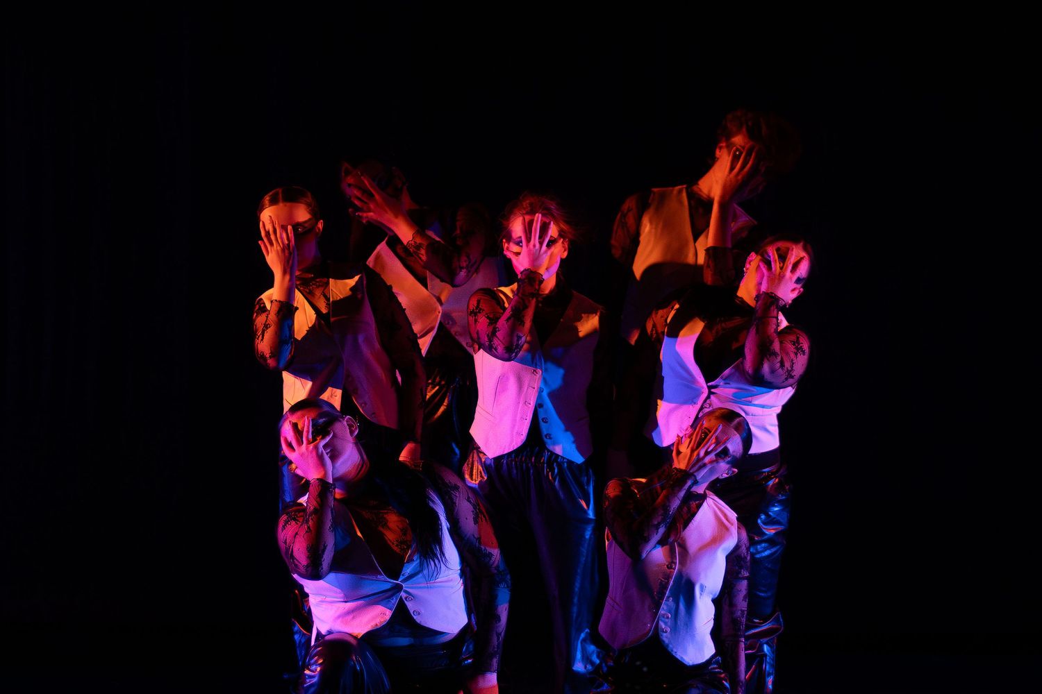 Dancers performing under dramatic blue and red stage lighting in a contemporary dance show.
