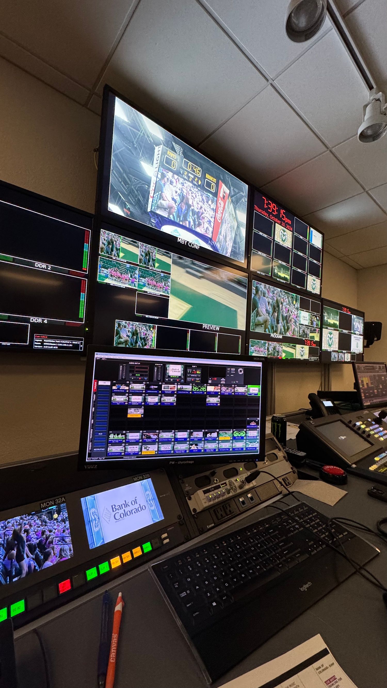 Broadcast production control room with multiple monitors showing live football game coverage and equipment.
