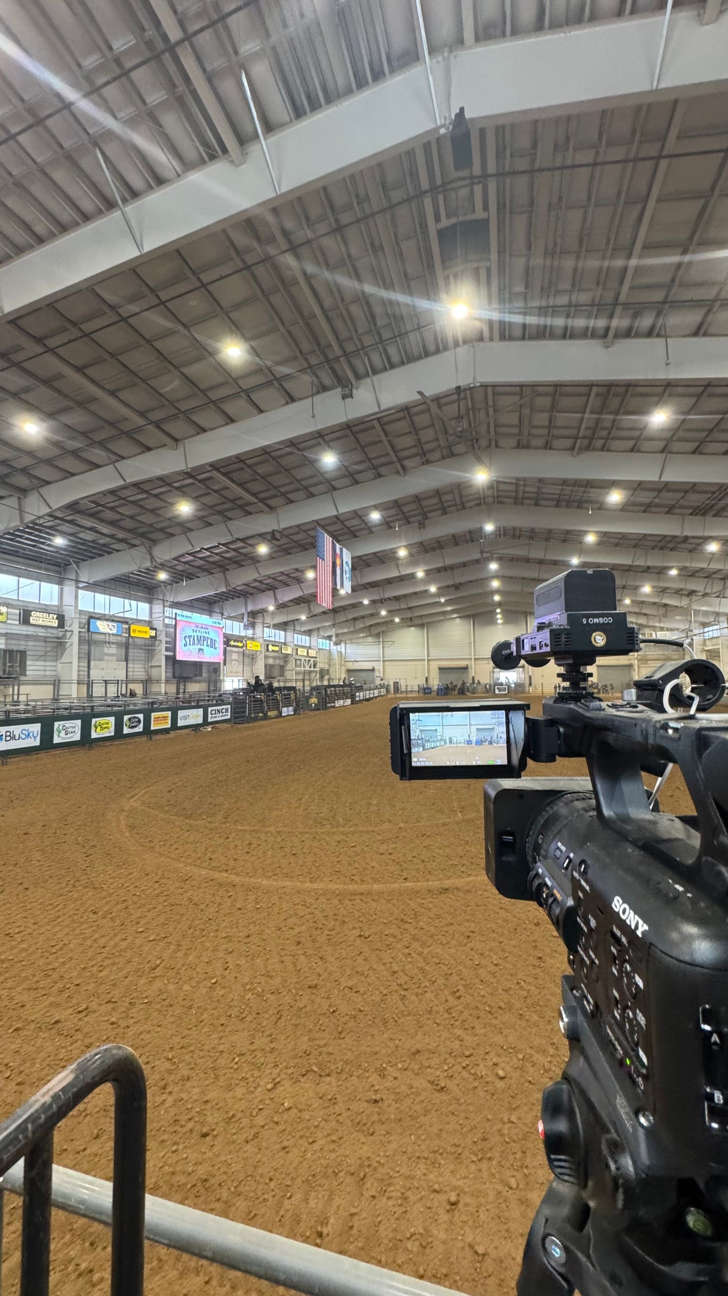 Sony professional video camera positioned courtside at an indoor equestrian arena with dirt floor.