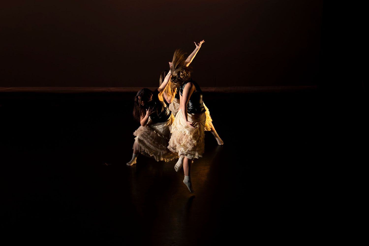 Two ballet dancers in yellow costumes perform an intimate contemporary dance piece under warm stage lighting.