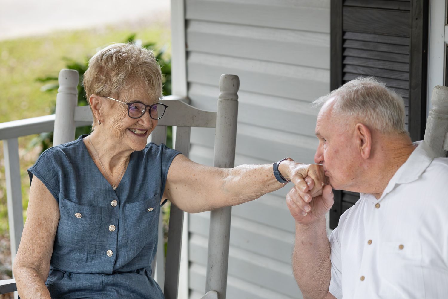 Grandparents sitting together on their front porch in Pensacola, FL