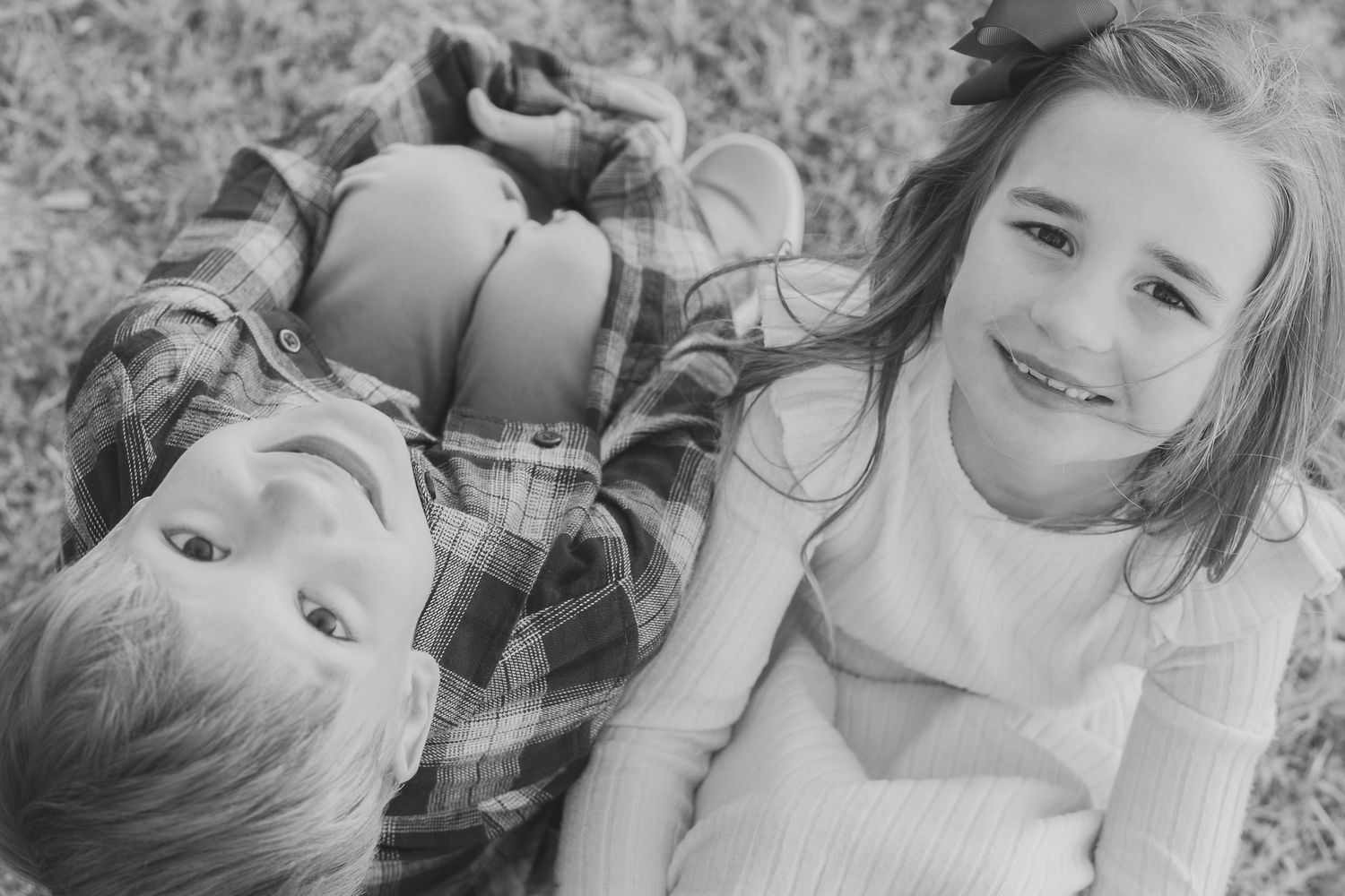 Two kids laughing in the grass during a relaxed family photo session in Northwest Florida