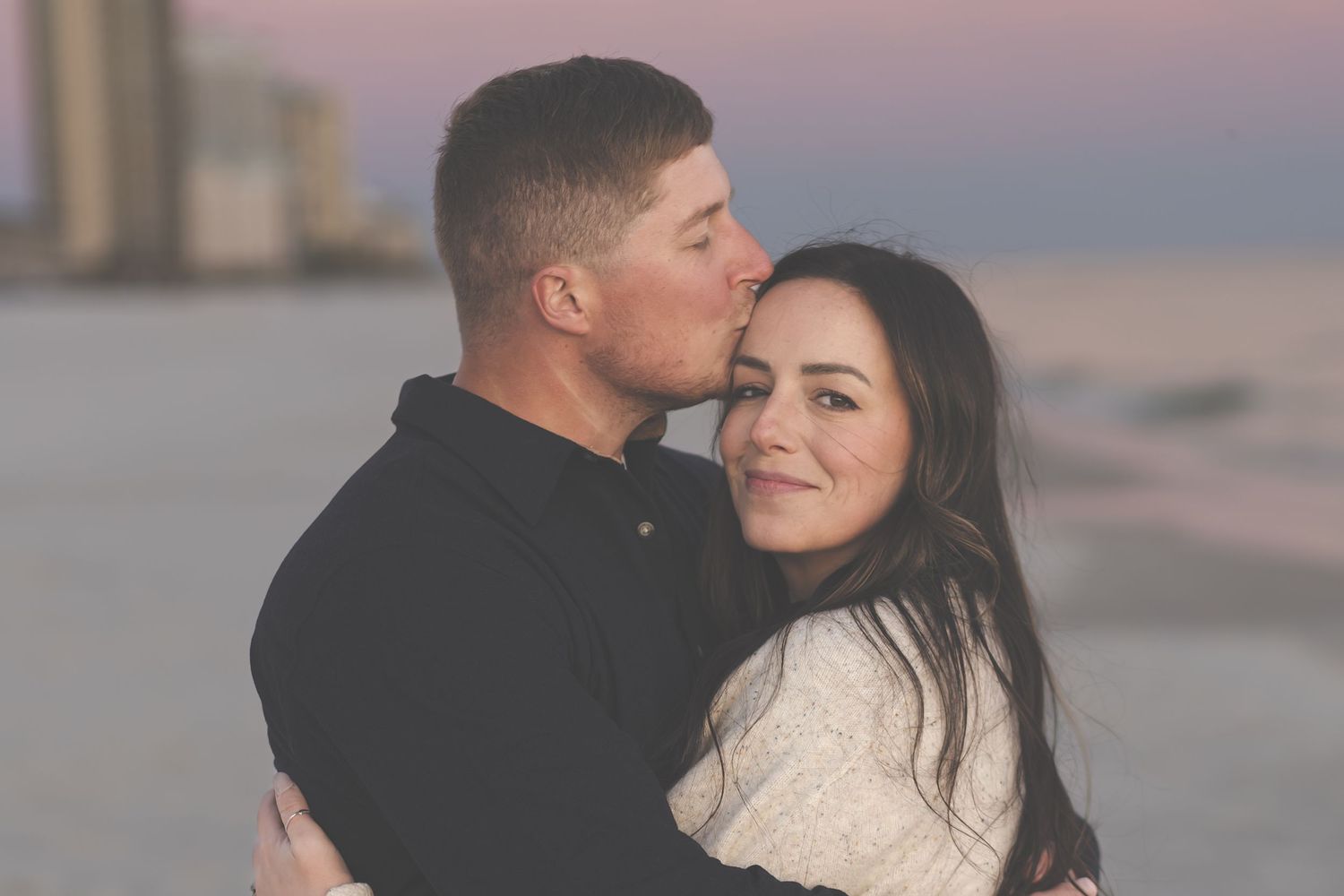 Couple cuddling cheek to cheek at sunset