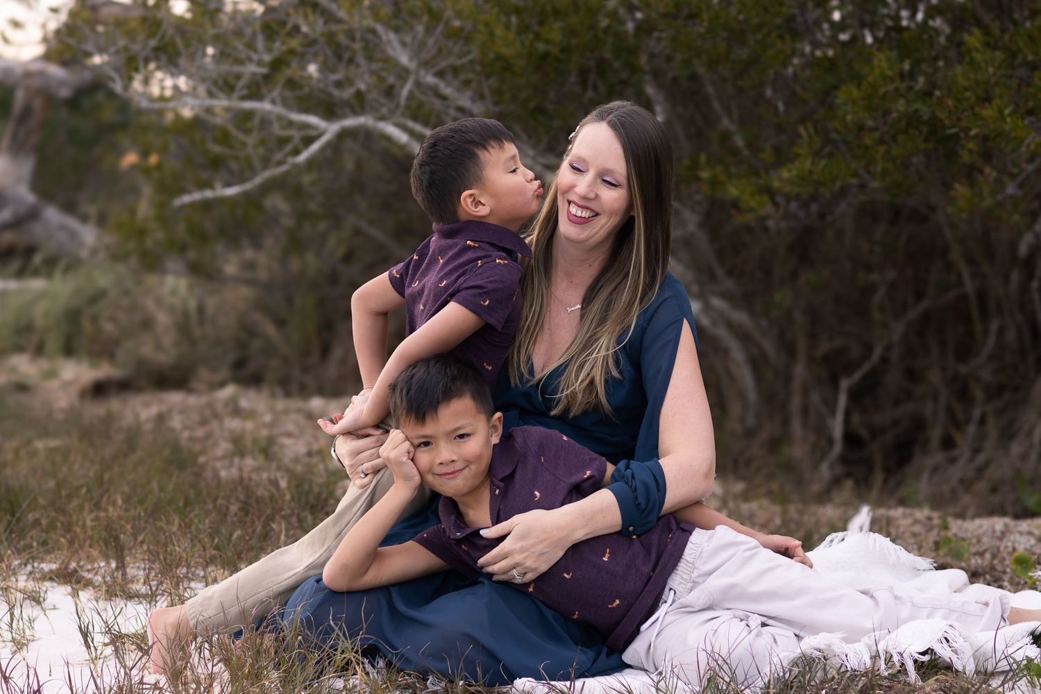 Expecting mom sitting on a blanket with her sons by the water
