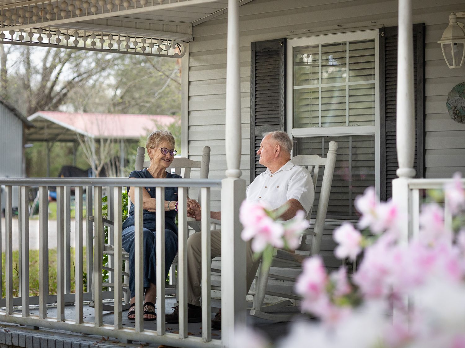 Senior couple sitting in rocking chairs on their front porch