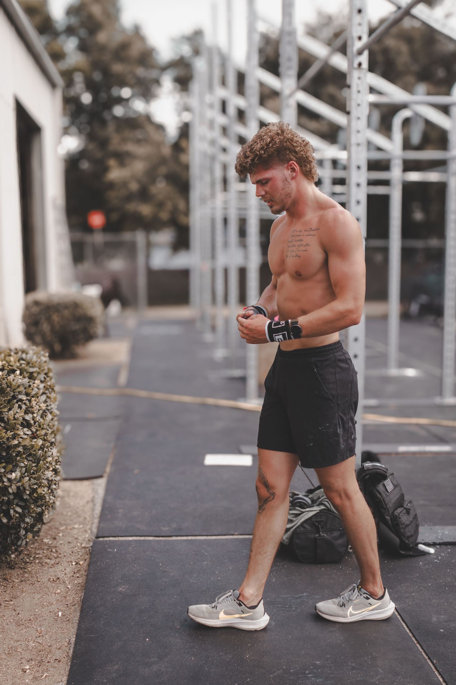 Shirtless athlete walking across a gym during a workout