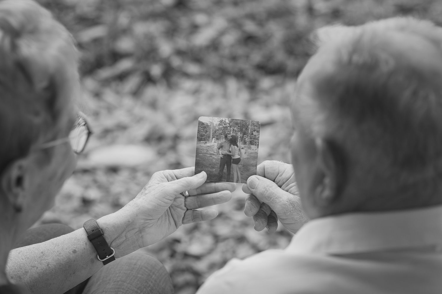 Black and white photo of a senior couple looking at an old photograph together