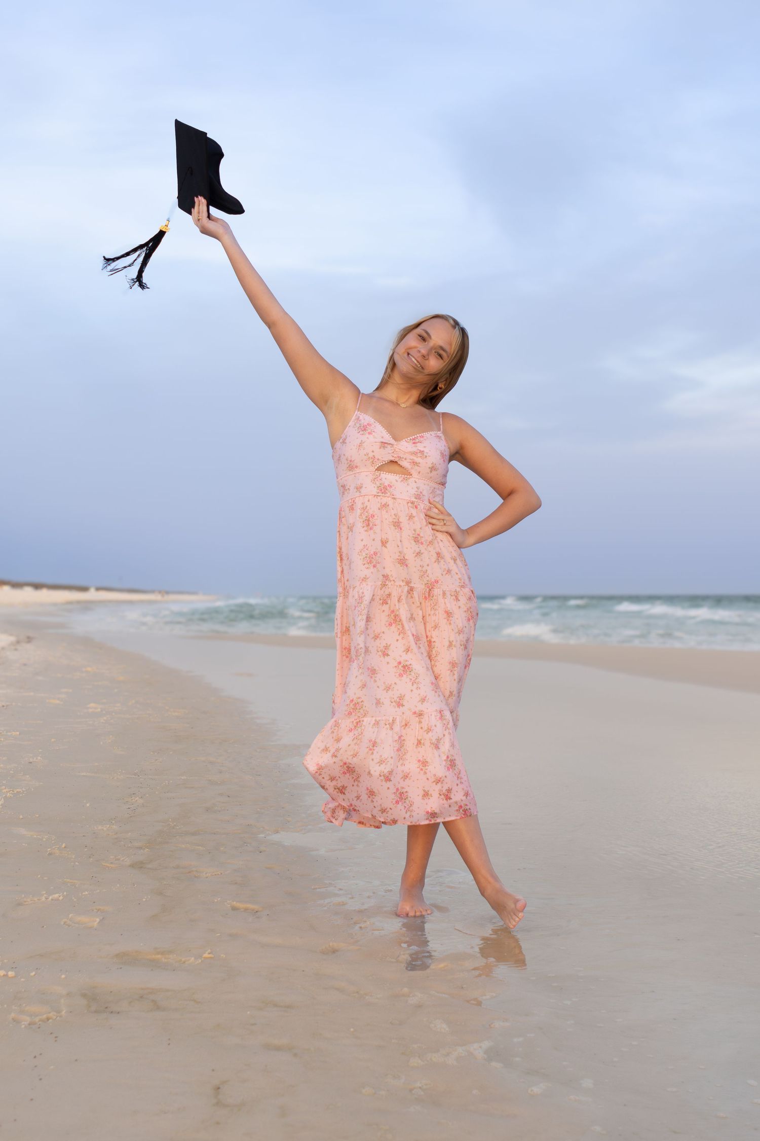 Graduate tossing her cap in the air on the beach, senior photos