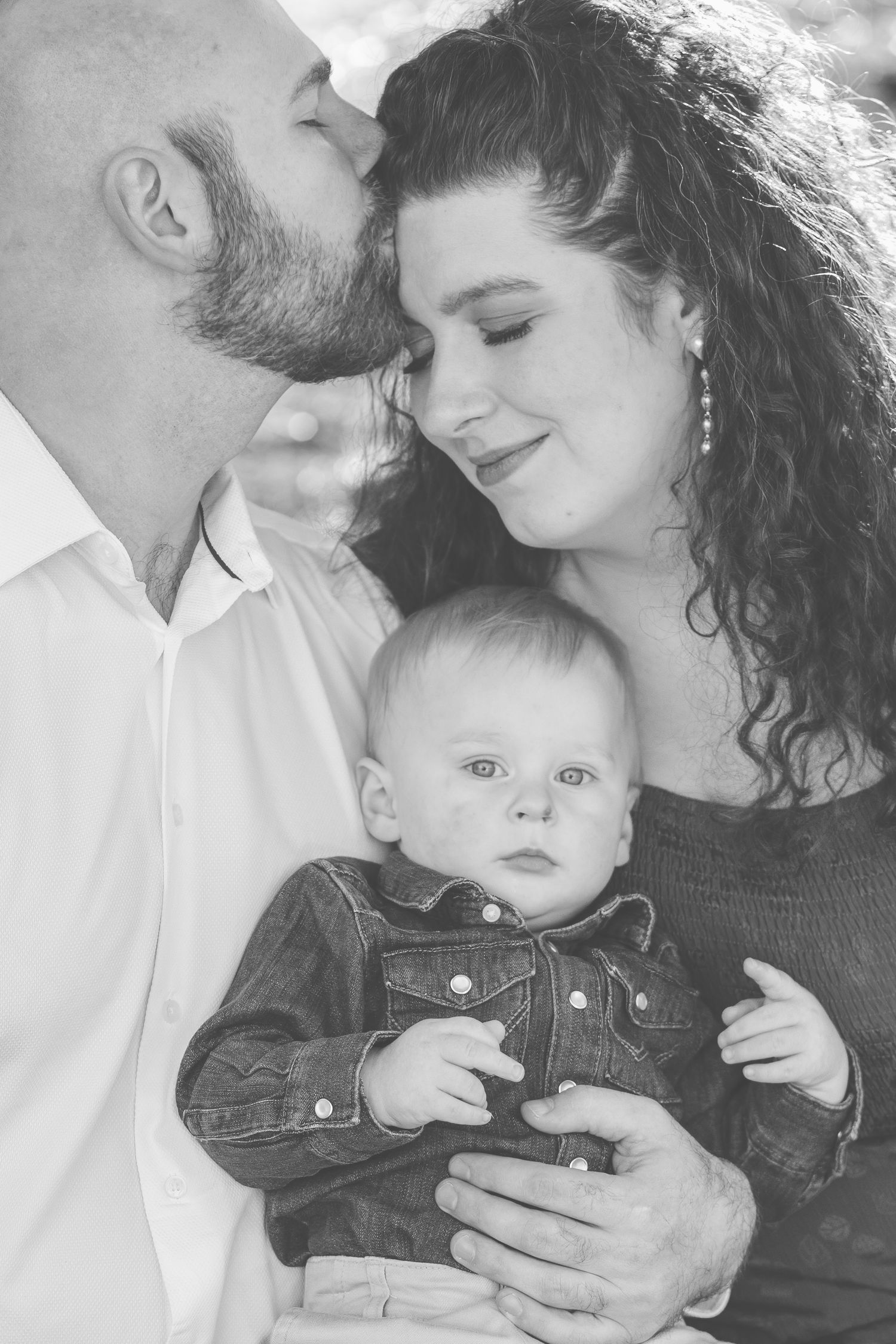 Black and white photo of parents snuggling their baby boy