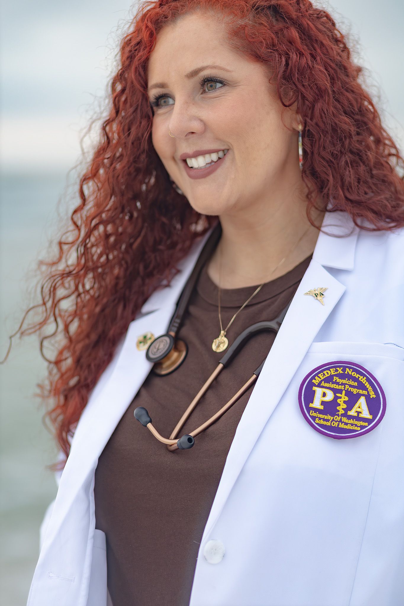Smiling medical graduate in her white coat by the beach