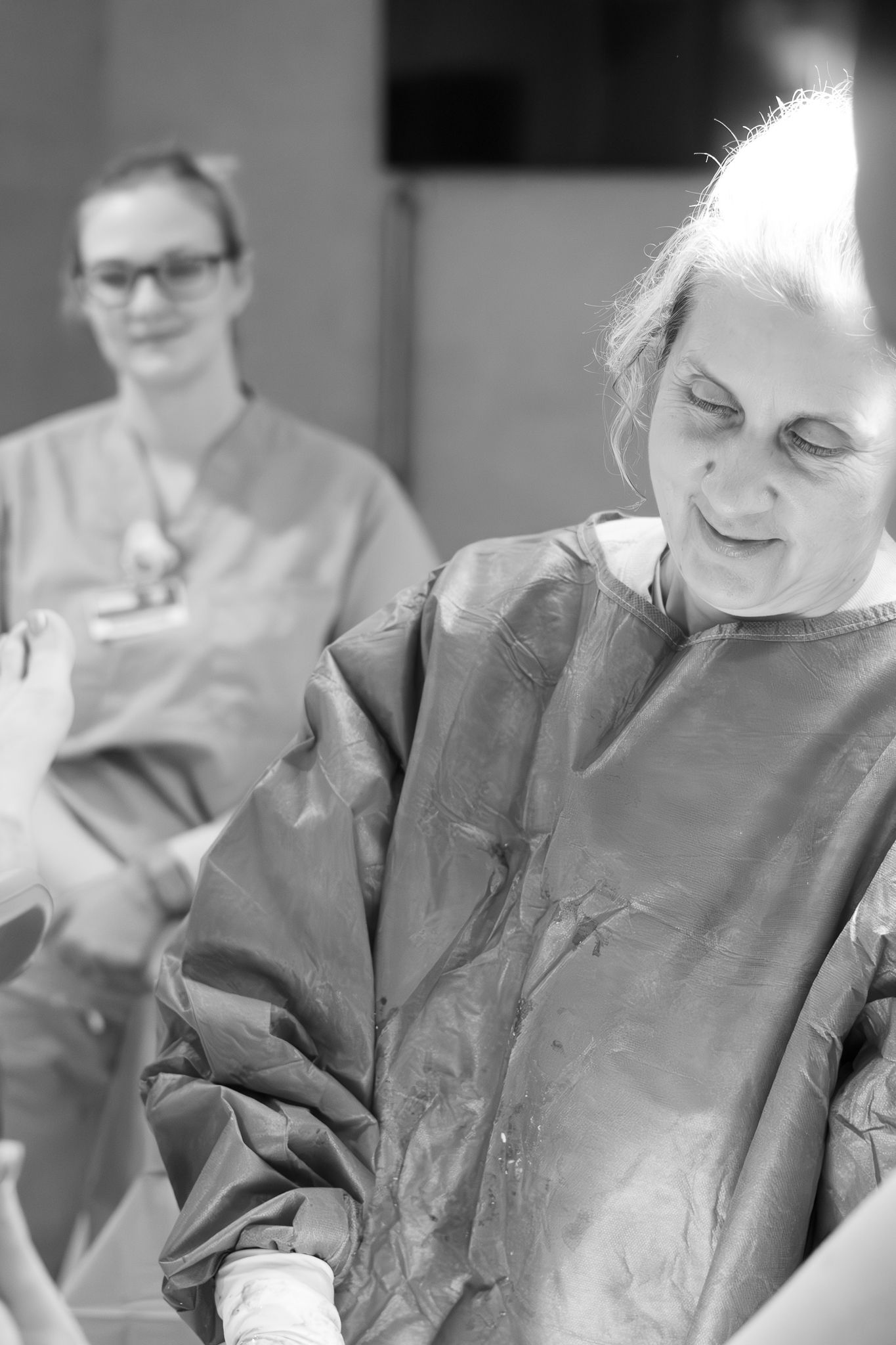 Black and white photo of a nurse and midwife assisting during birth