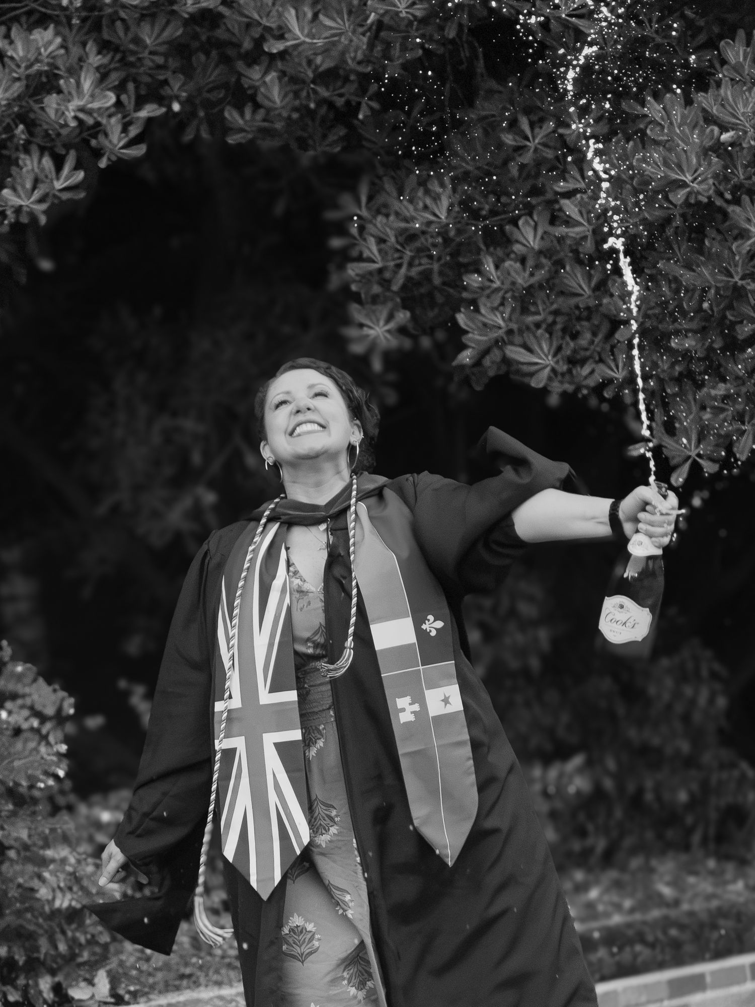 Black and white photo of a graduate spraying champagne to celebrate