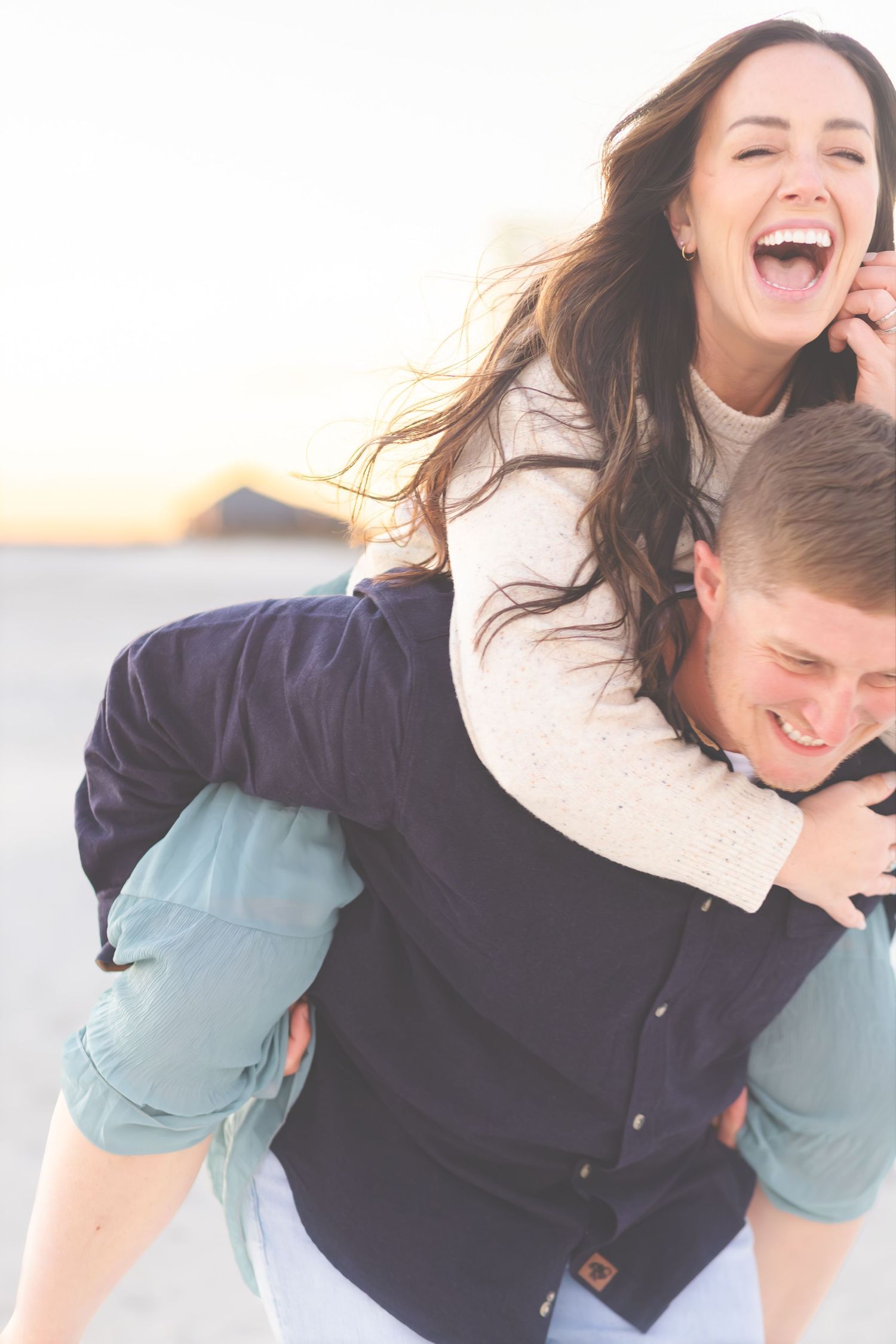 Woman laughing during a piggyback ride on the beach