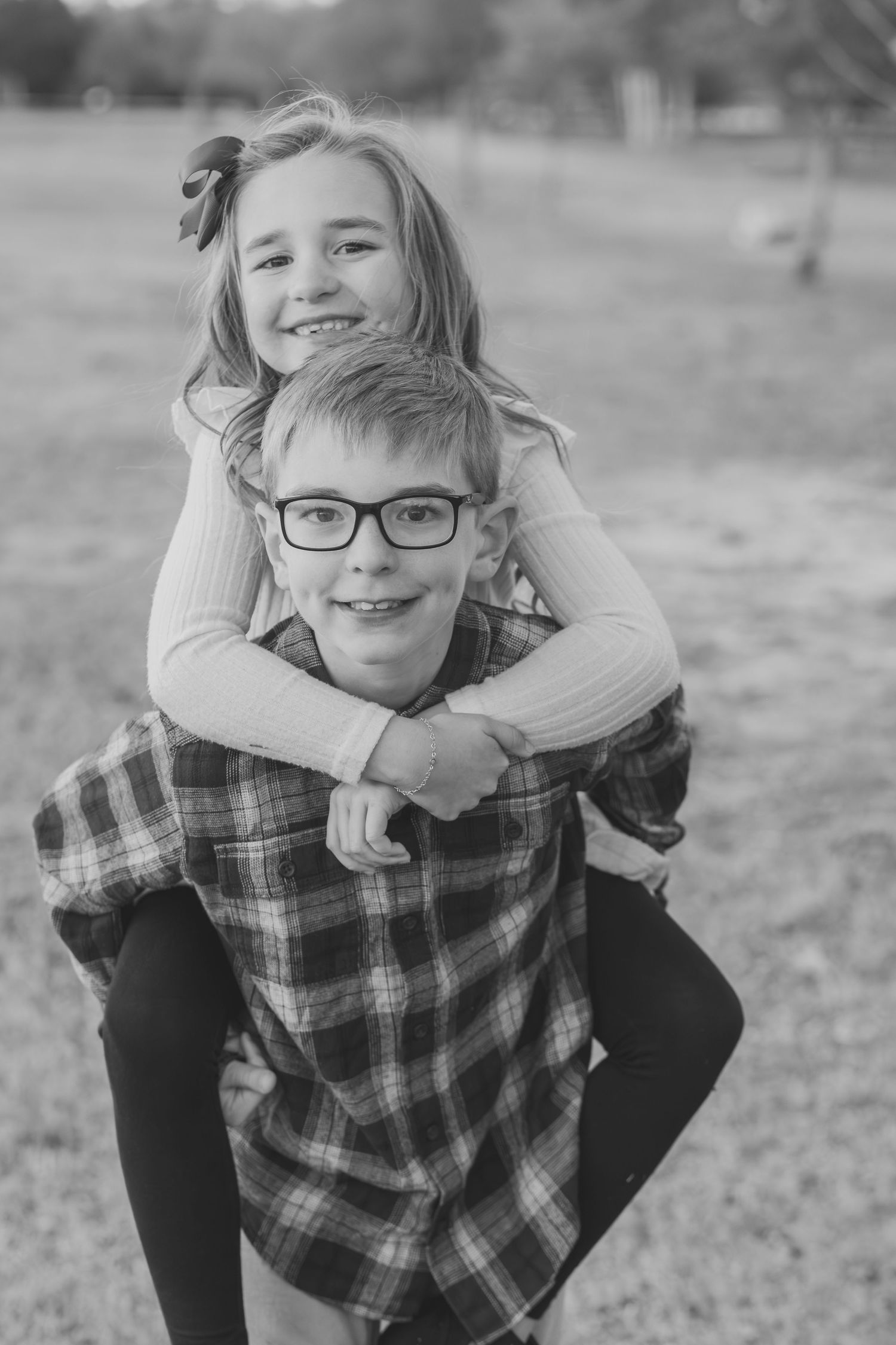 Sister riding piggyback on her big brother, black and white