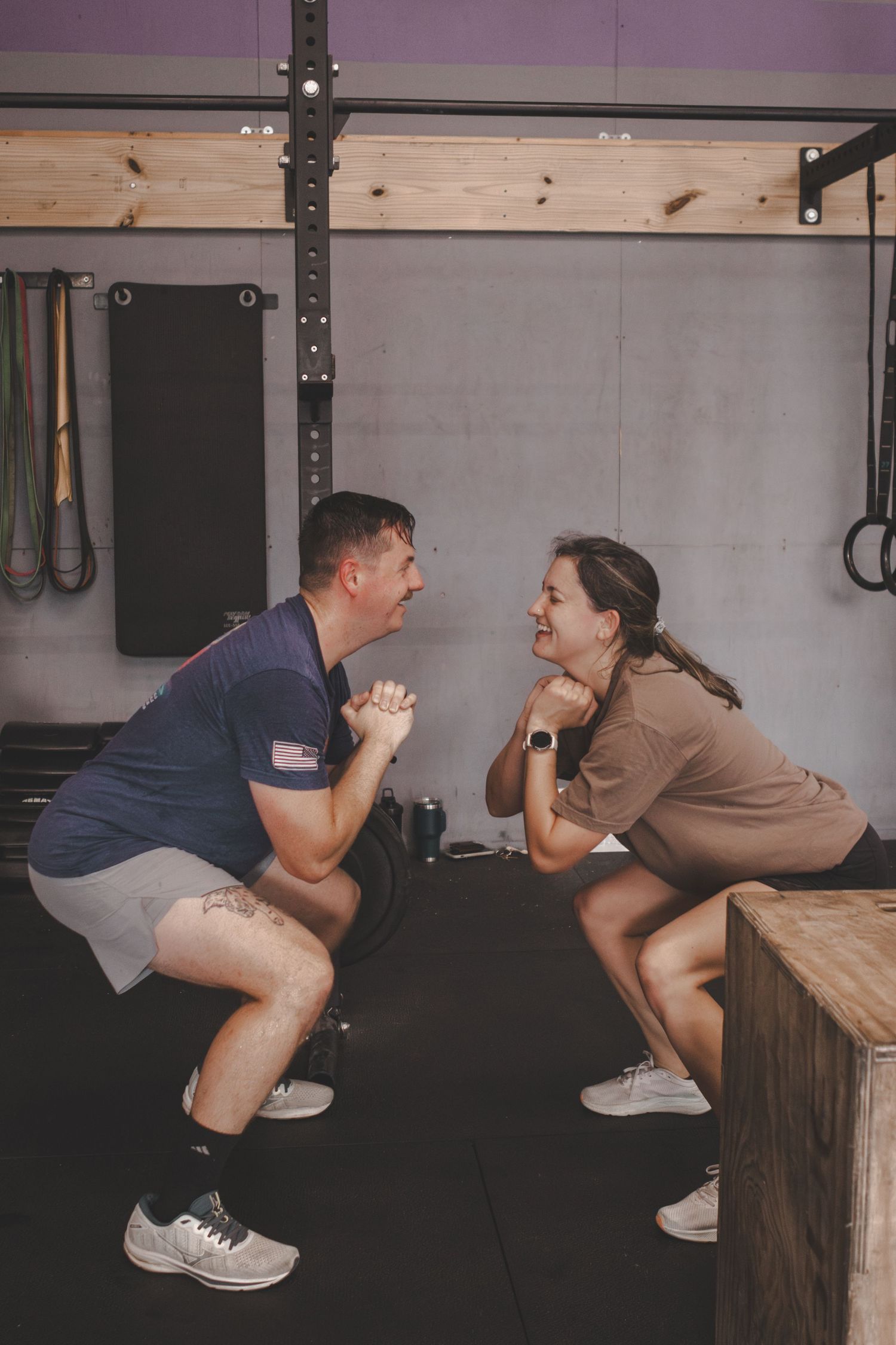 Two athletes doing wall sits side by side at the gym