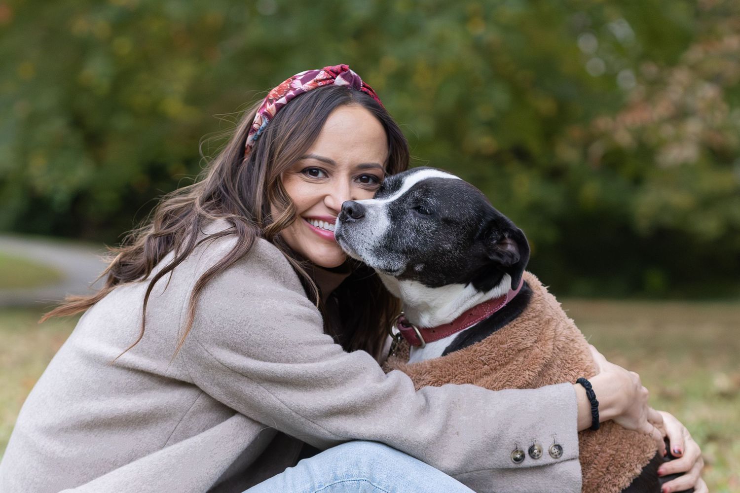 Woman hugging her dog cheek to cheek in the park
