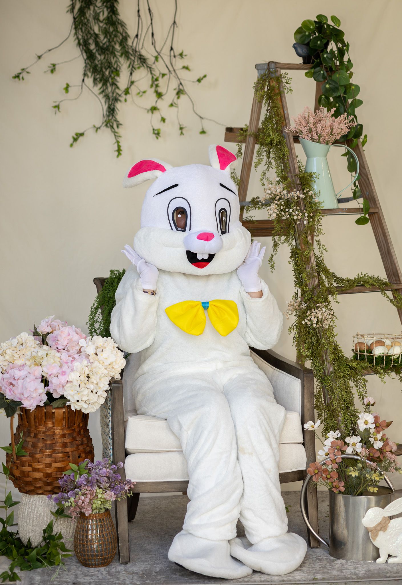 Easter Bunny sitting in a decorated spring photo setup at an event