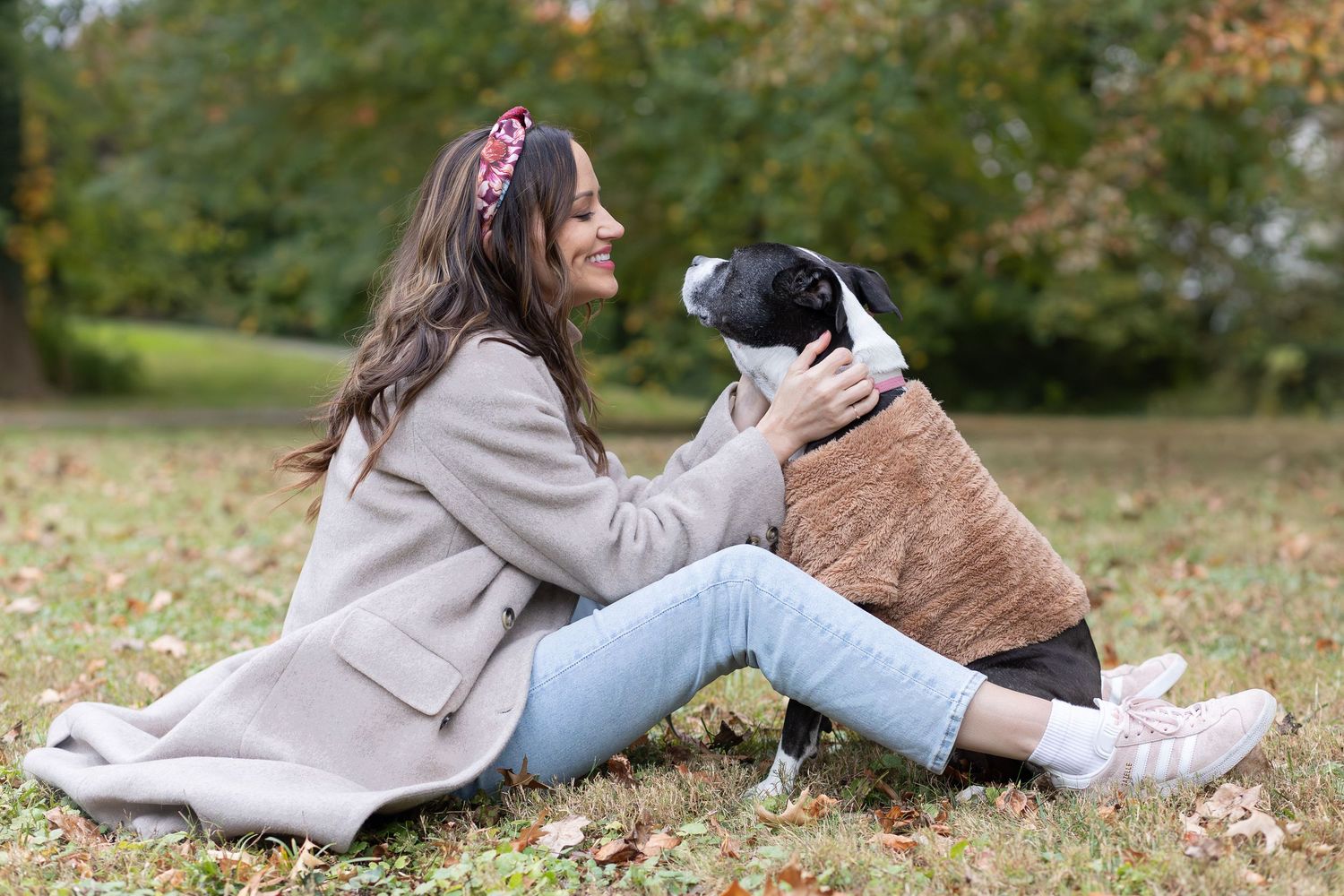 Woman sitting in the grass laughing with her dog