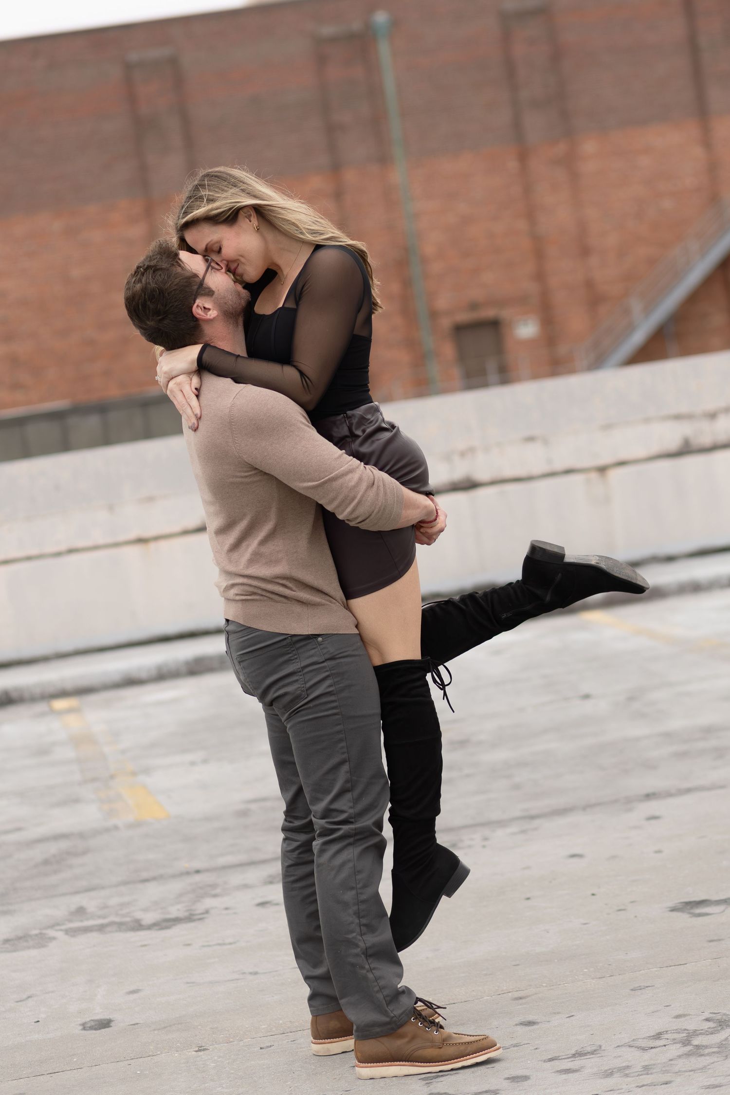Man lifting his partner in a kiss on a downtown Pensacola rooftop